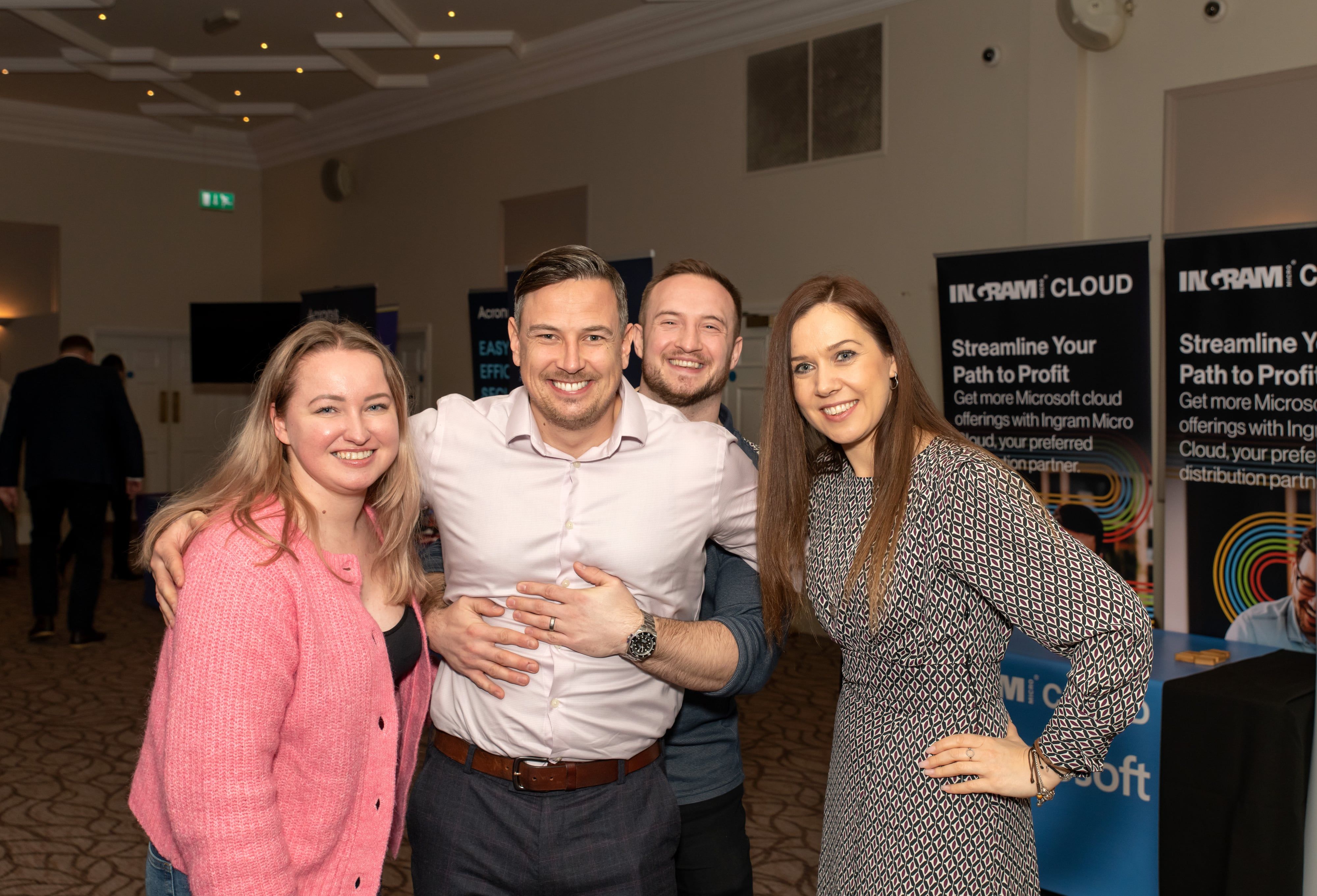 Four colleagues pose by Ingram Cloud branded banners at corporate networking event