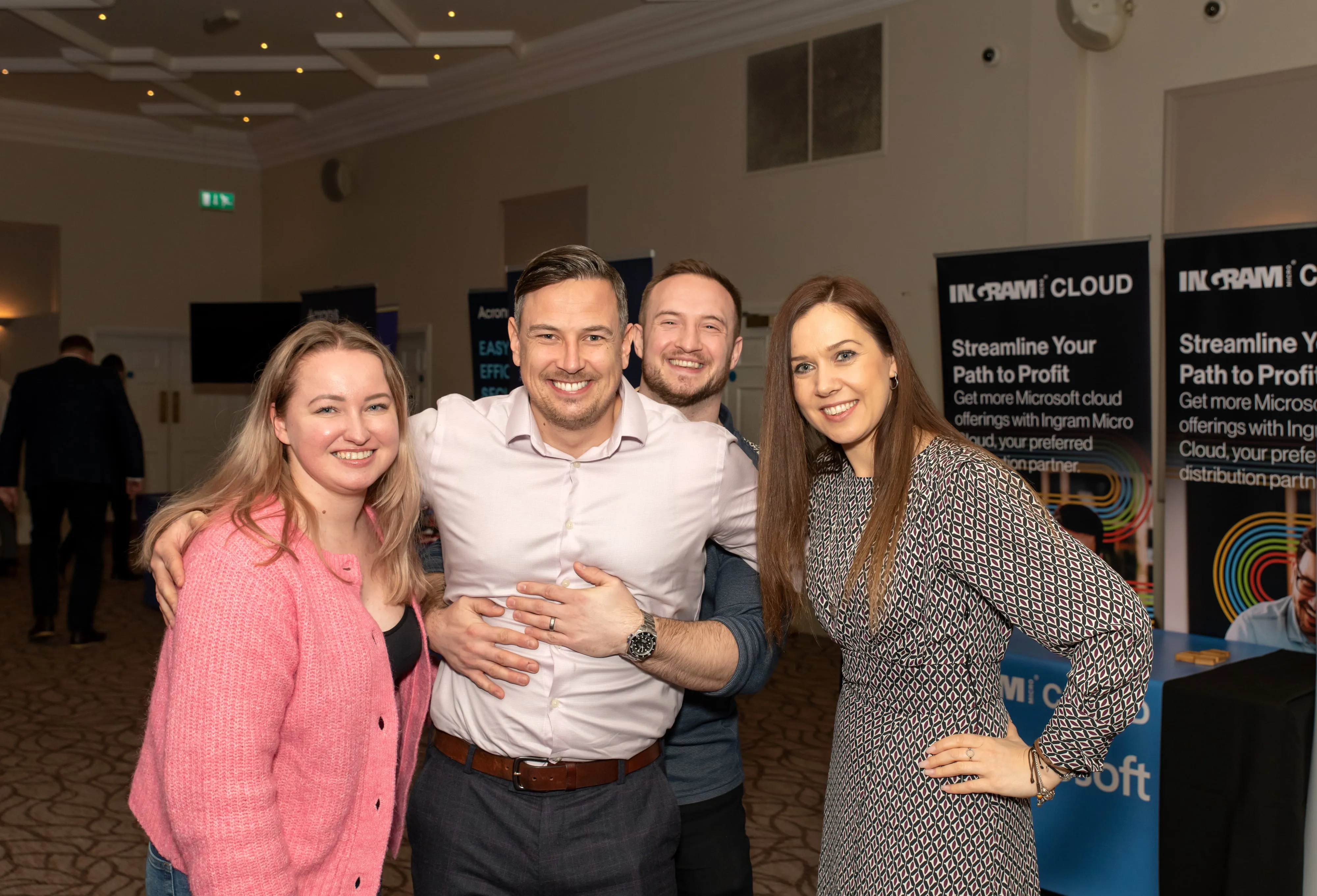 Four colleagues pose by Ingram Cloud branded banners at corporate networking event