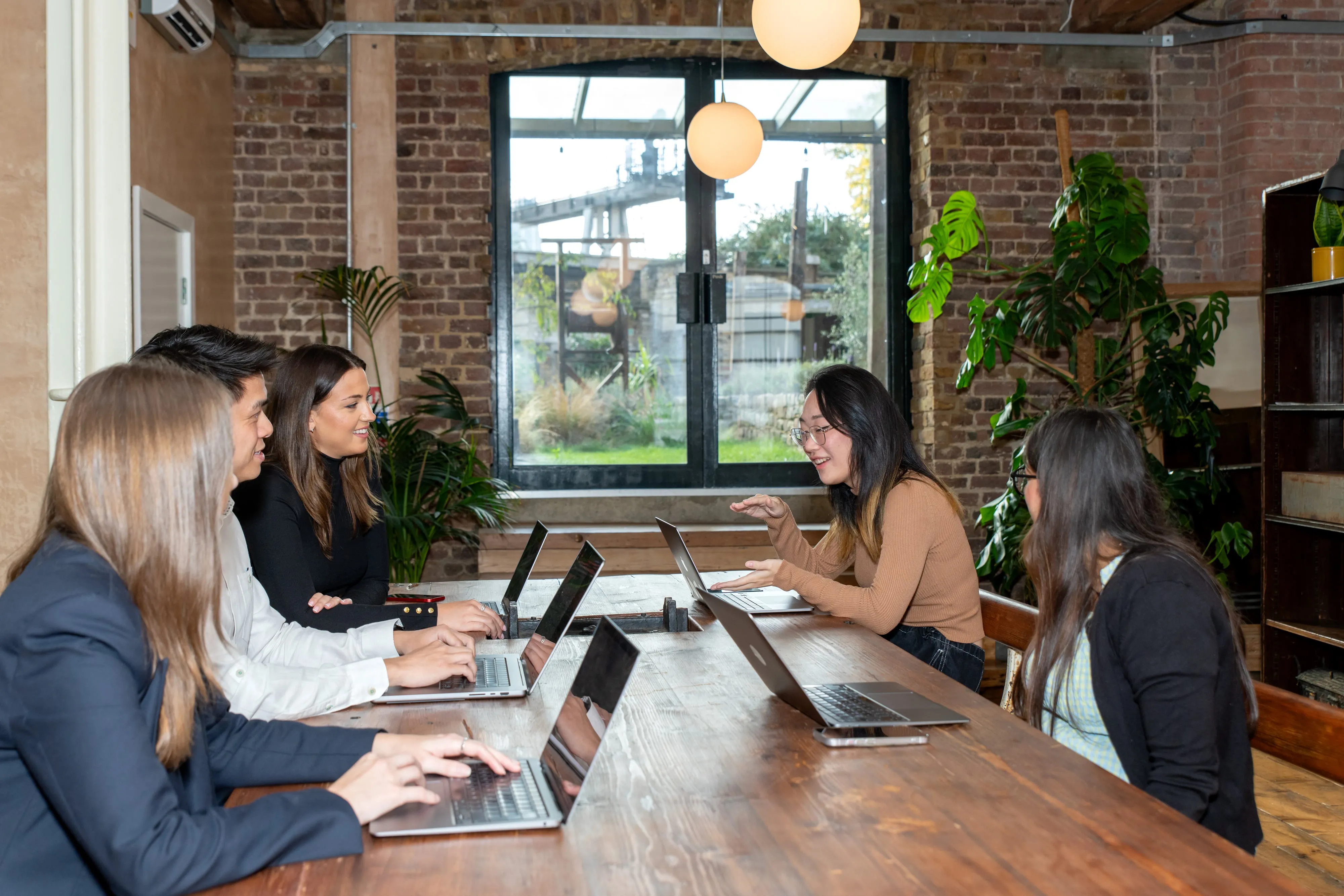 Sprout.ai colleagues collaborating on laptops around long wooden table