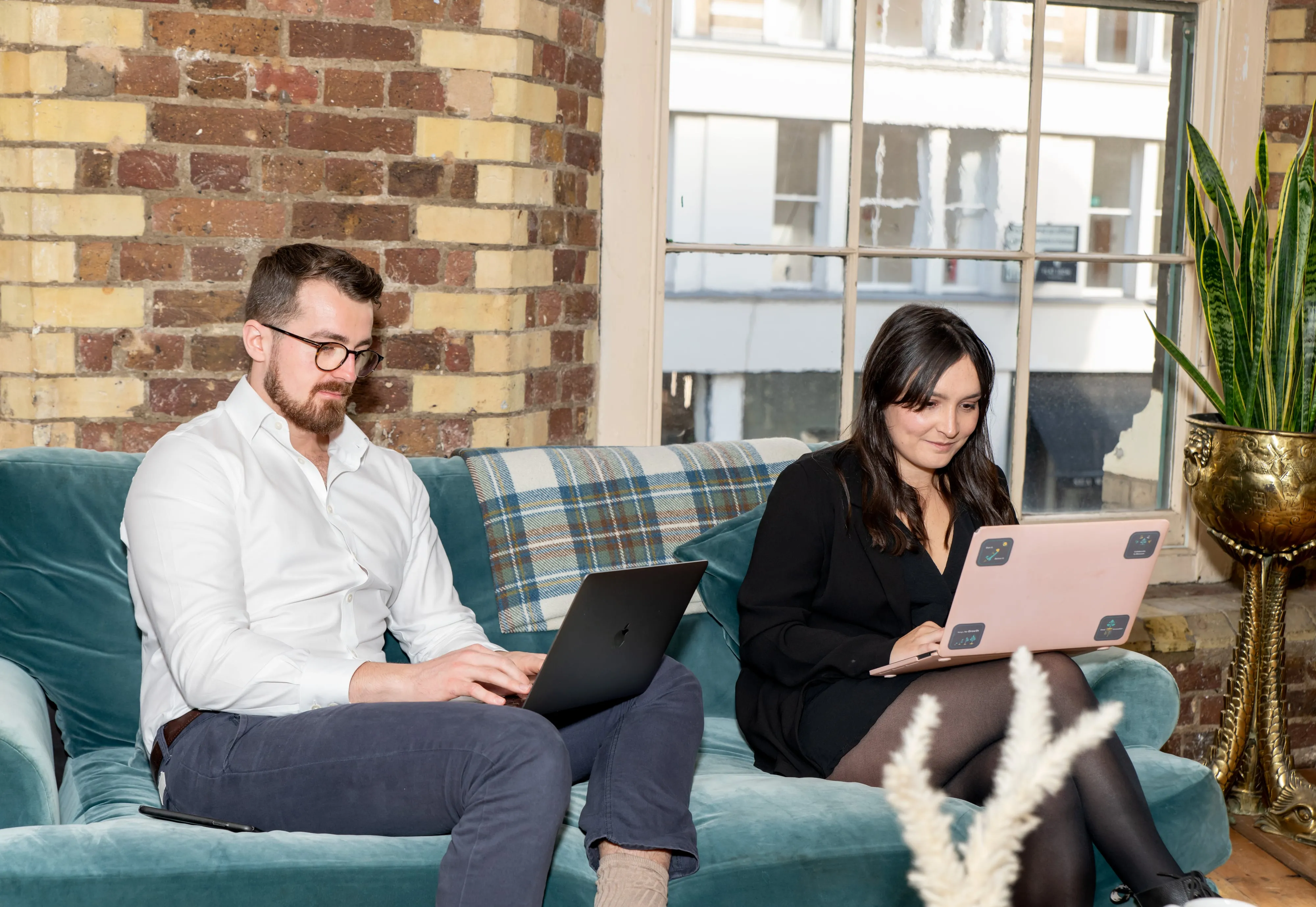 Sprout AI colleagues collaborate on laptops around long wooden table in industrial office
