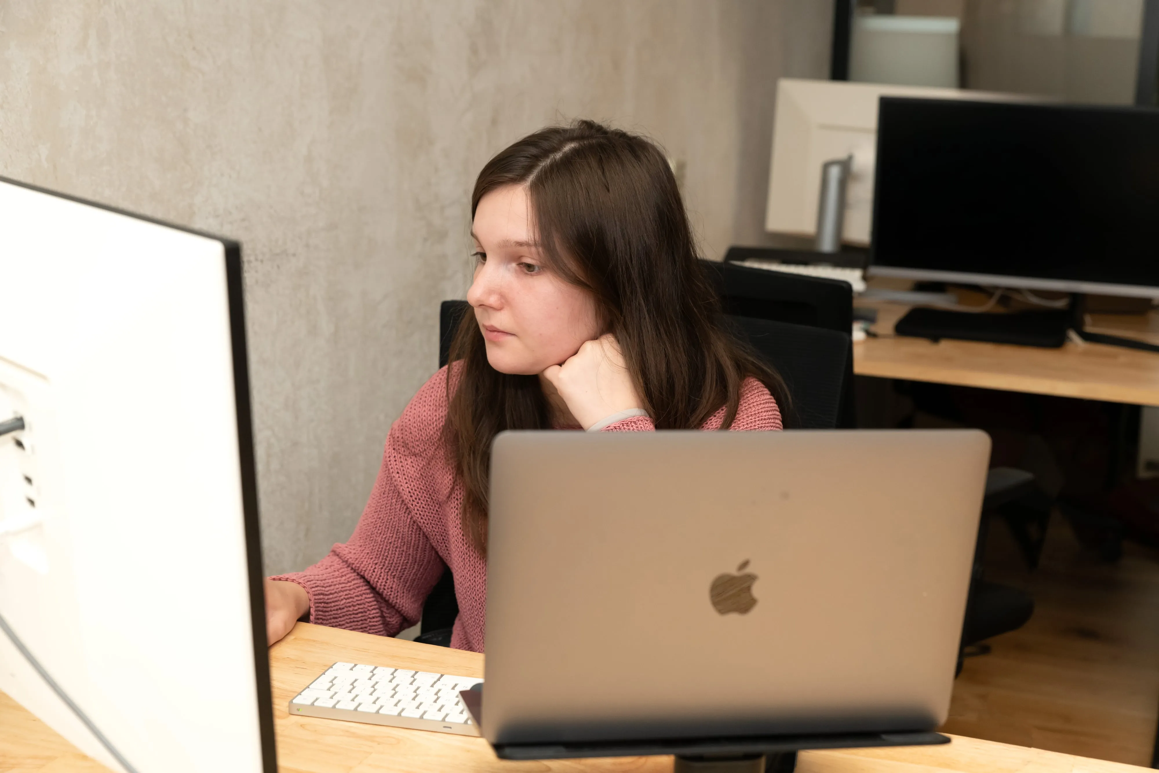 Sprout AI colleagues collaborating around a dark conference table at one laptop, mid-conversation in their coworking space