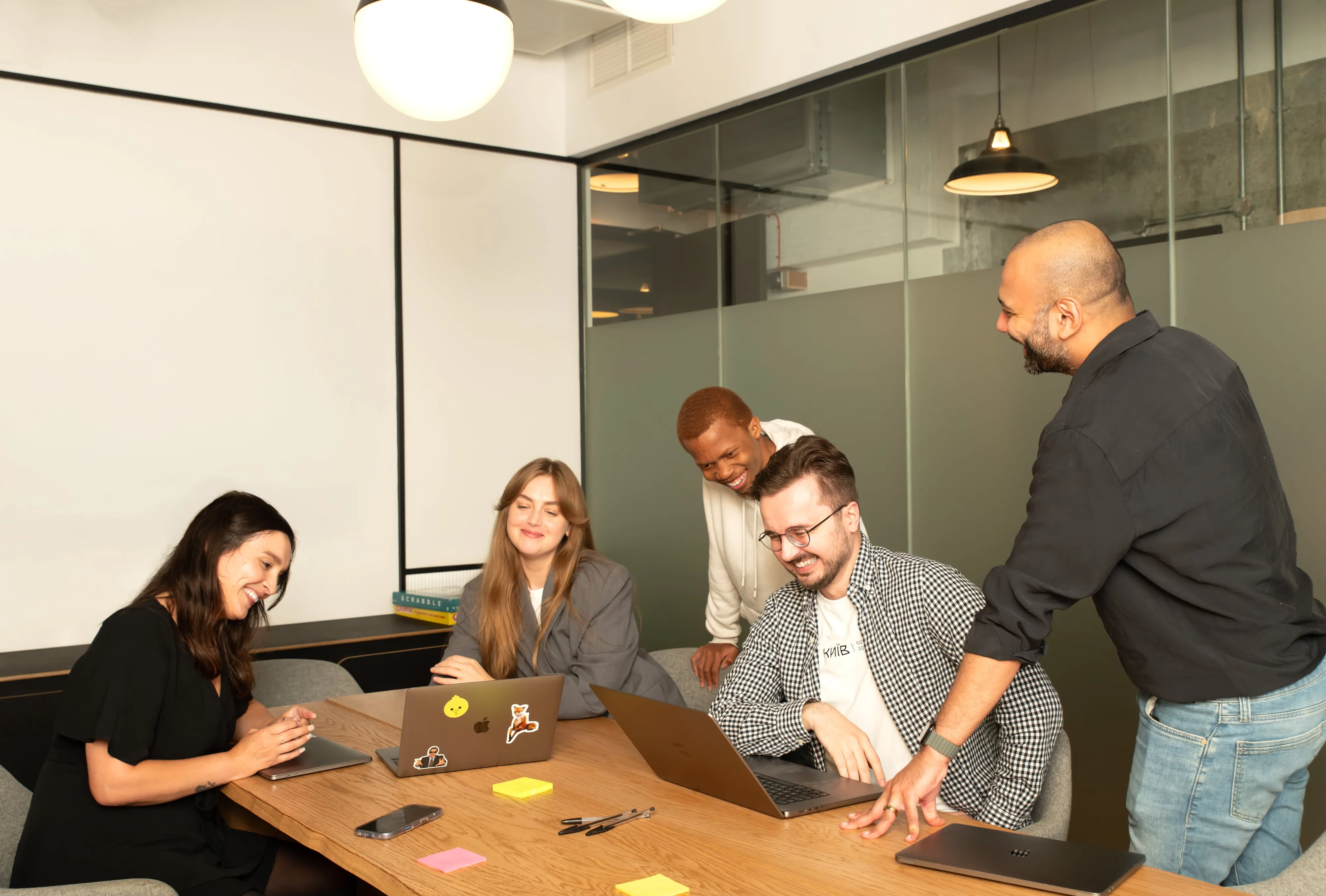 Sprout AI team brainstorming around a meeting-room table with sticky notes and laptops, glass partition behind