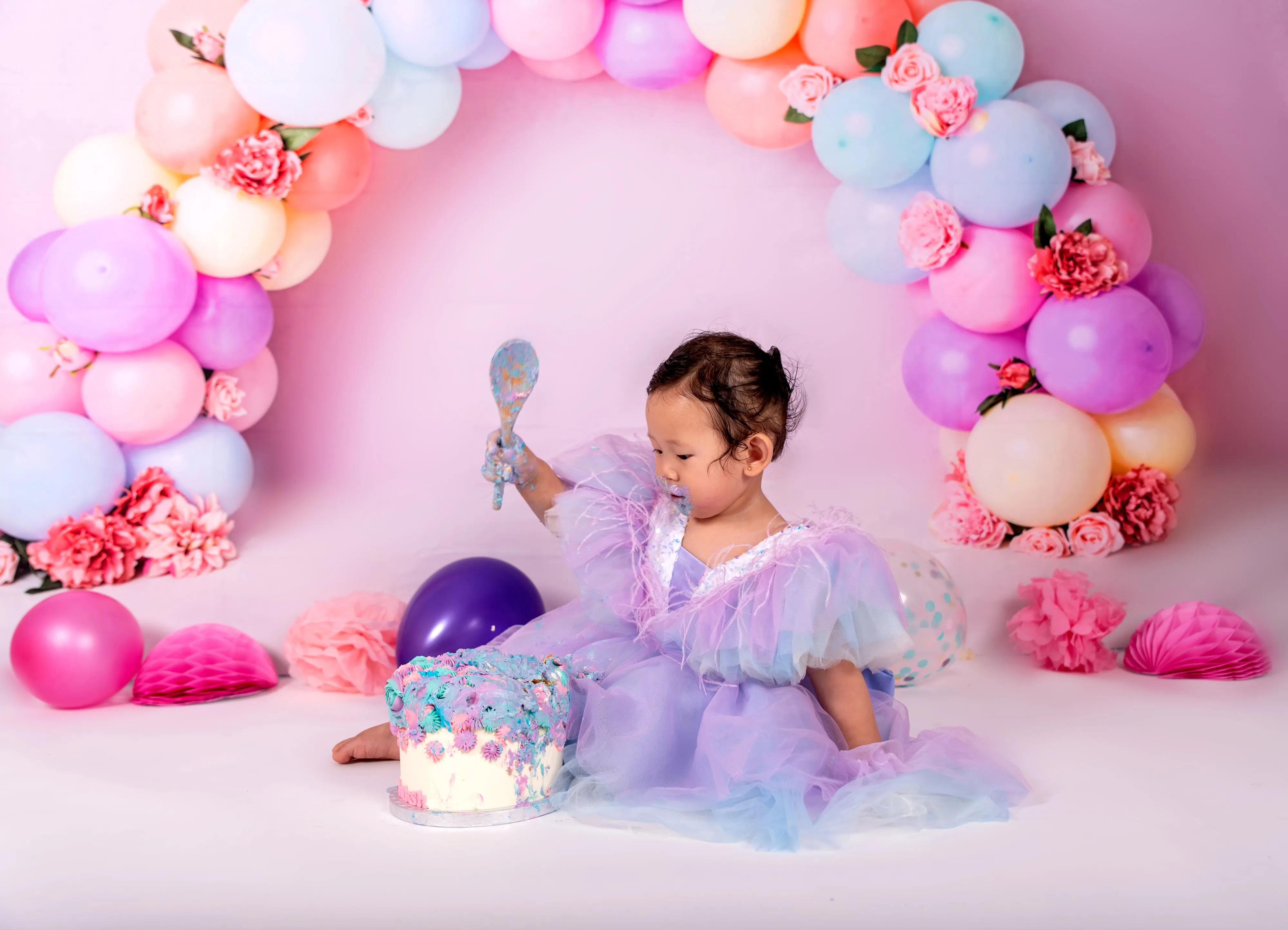 First-birthday studio milestone portrait with balloons
