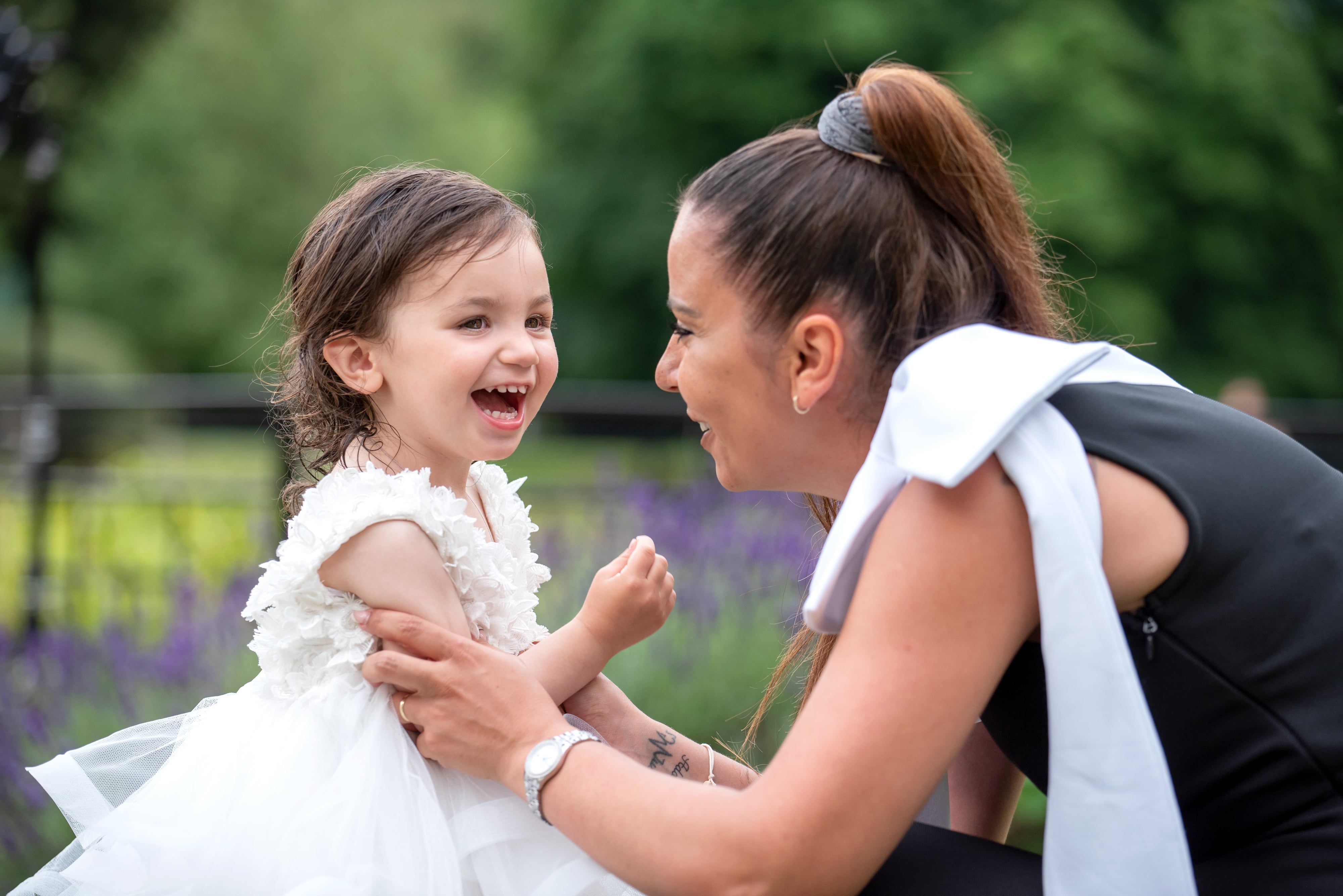Toddler giggling face-to-face with a loved one in the garden, lavender soft behind them