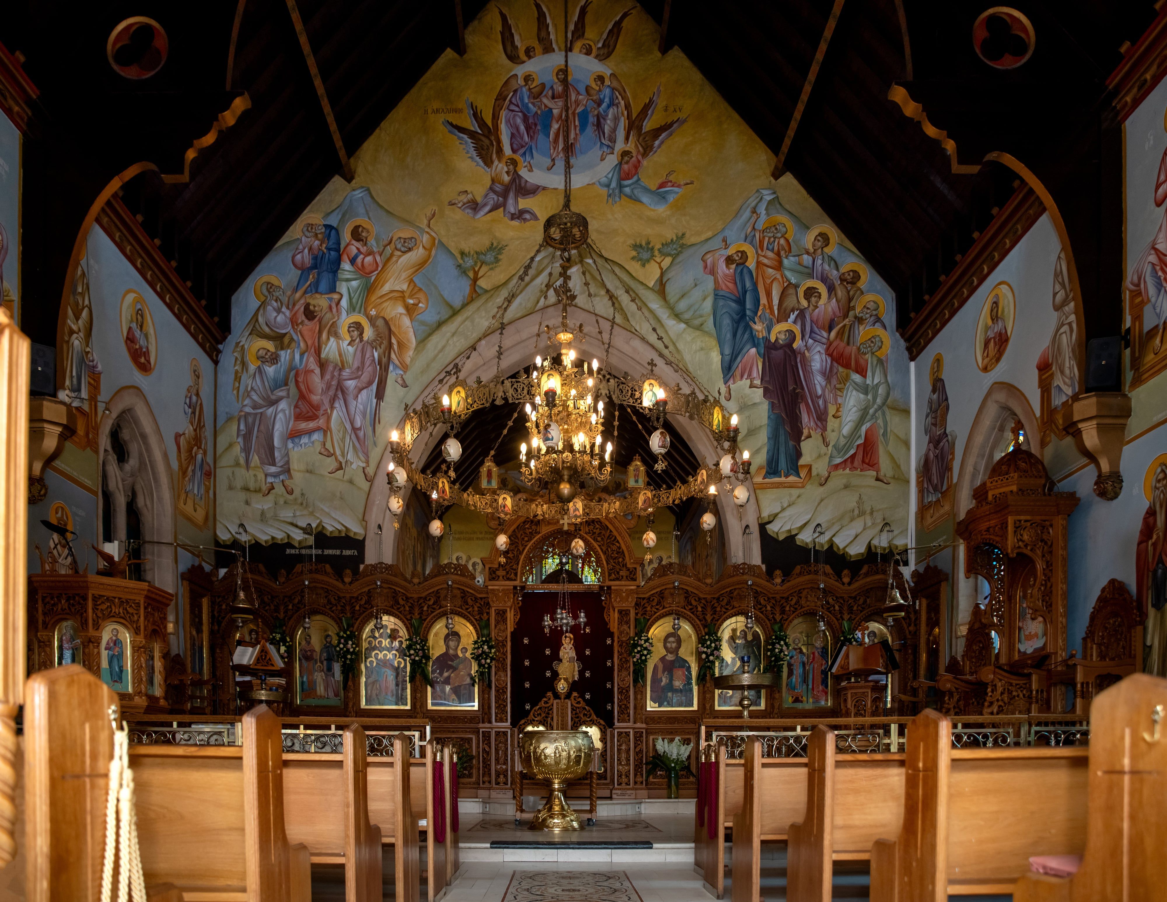 Interior of an Orthodox church, painted apse and gilded iconostasis rising above the baptismal font