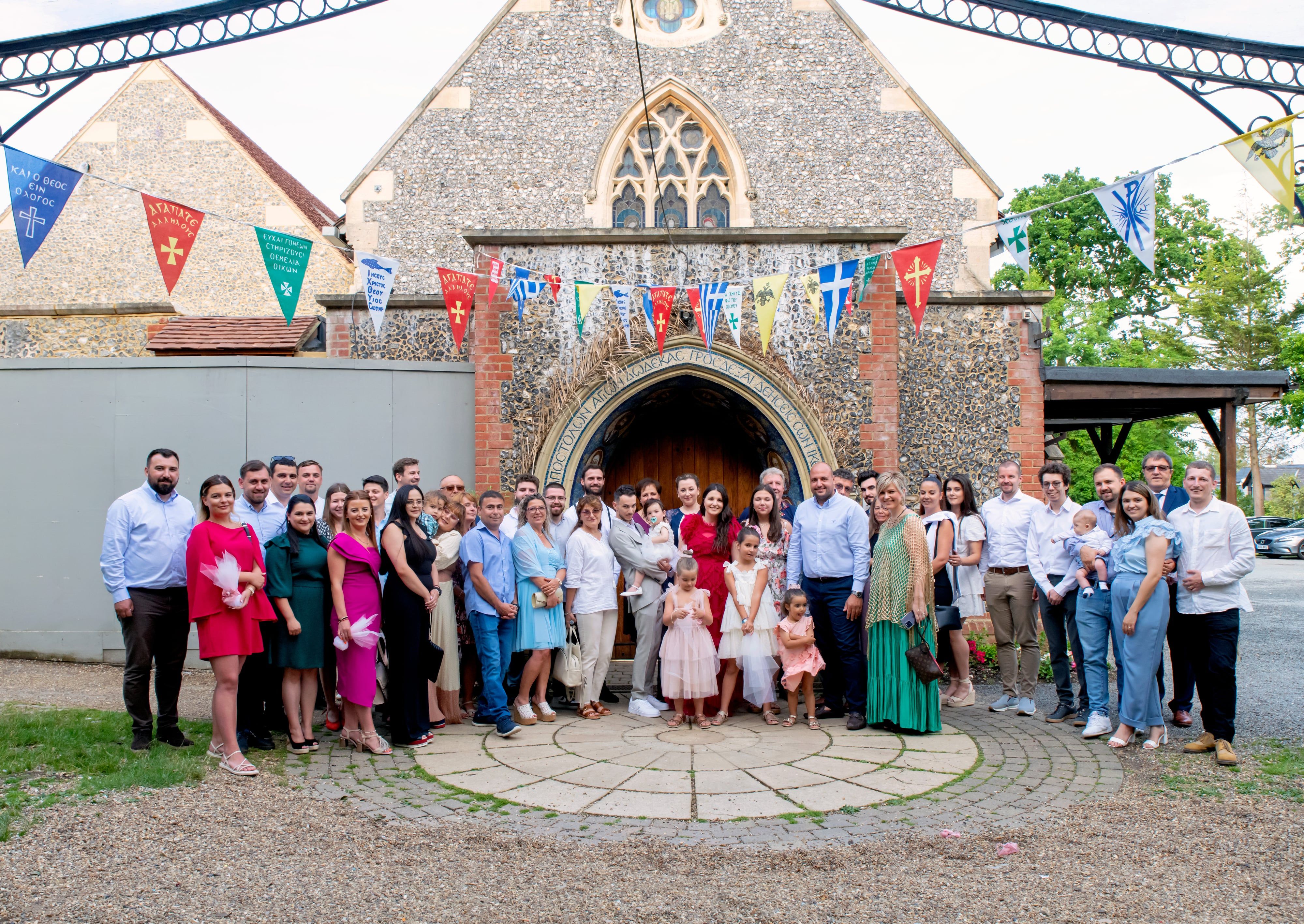 The whole christening party gathered outside the flint country church beneath strings of bunting