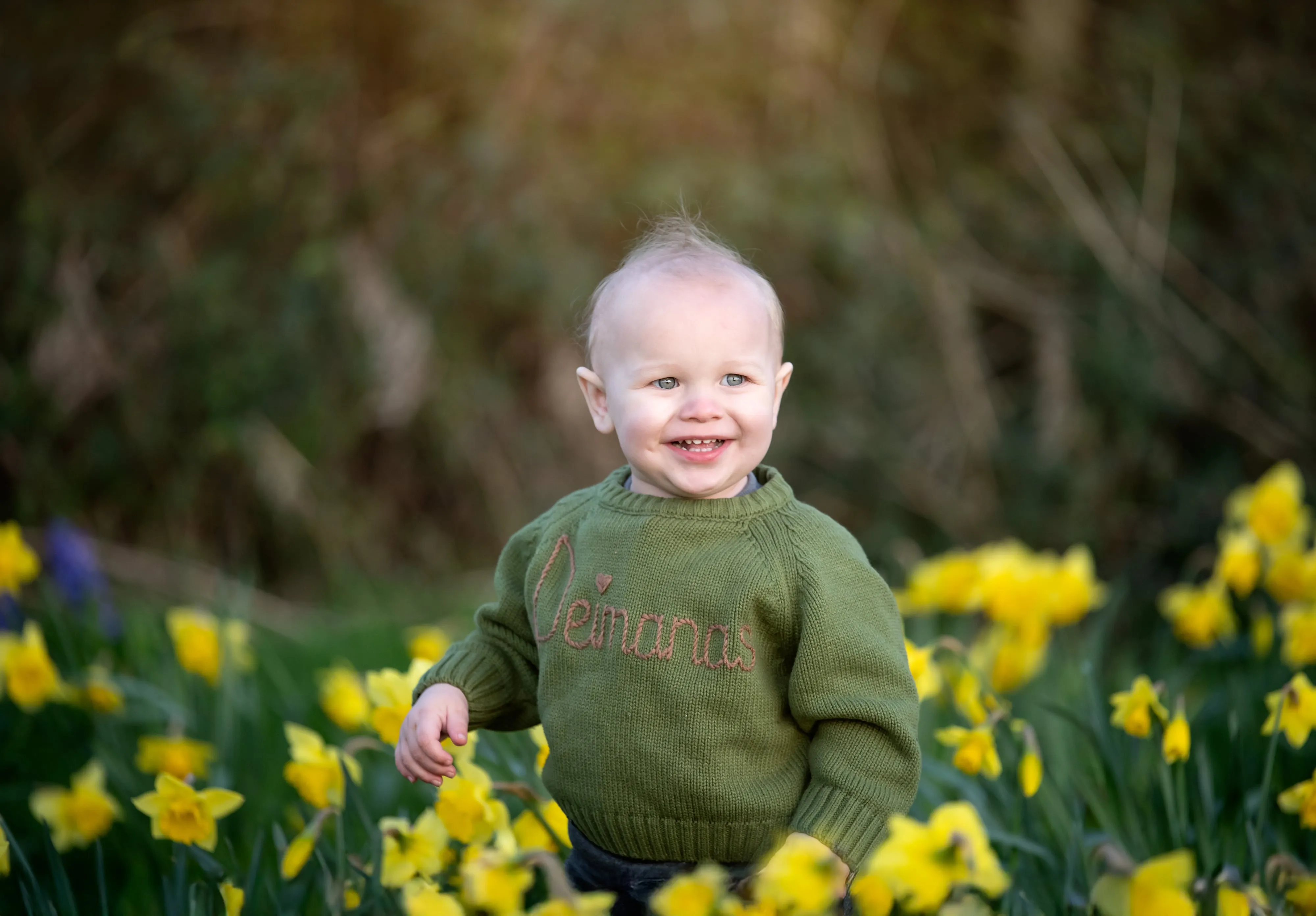 Toddler in green jumper in field of daffodils