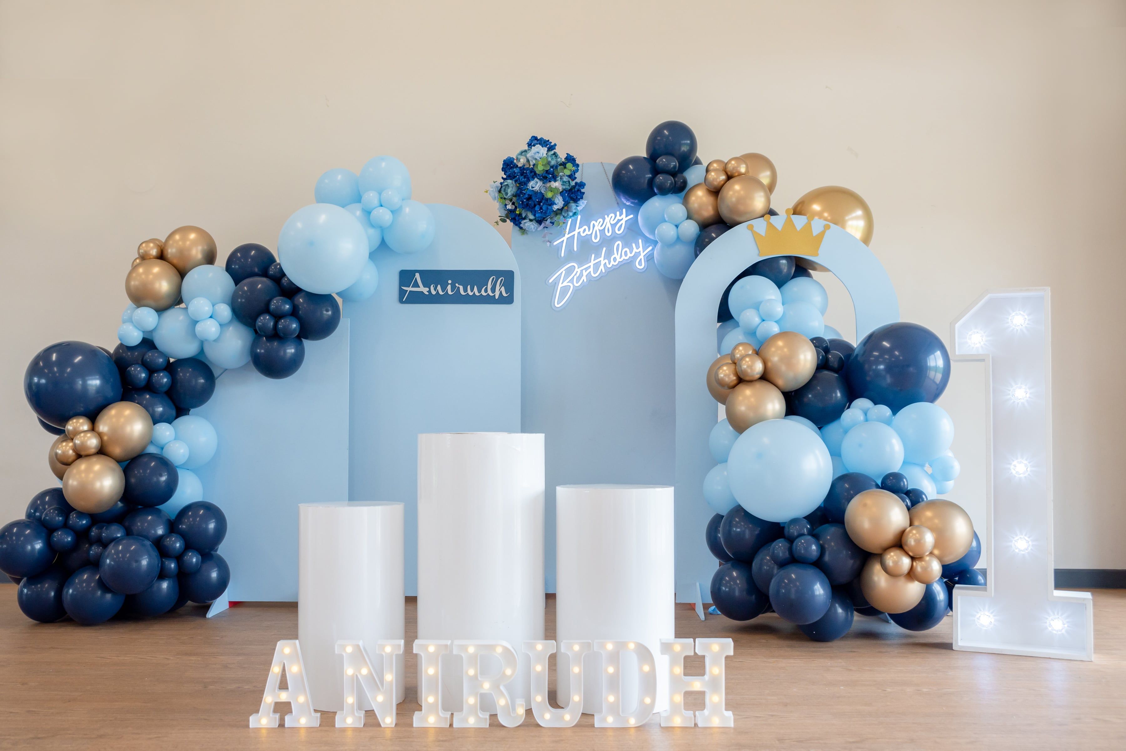 Blue-and-gold balloon arches and a light-up number one set the scene for a first-birthday party