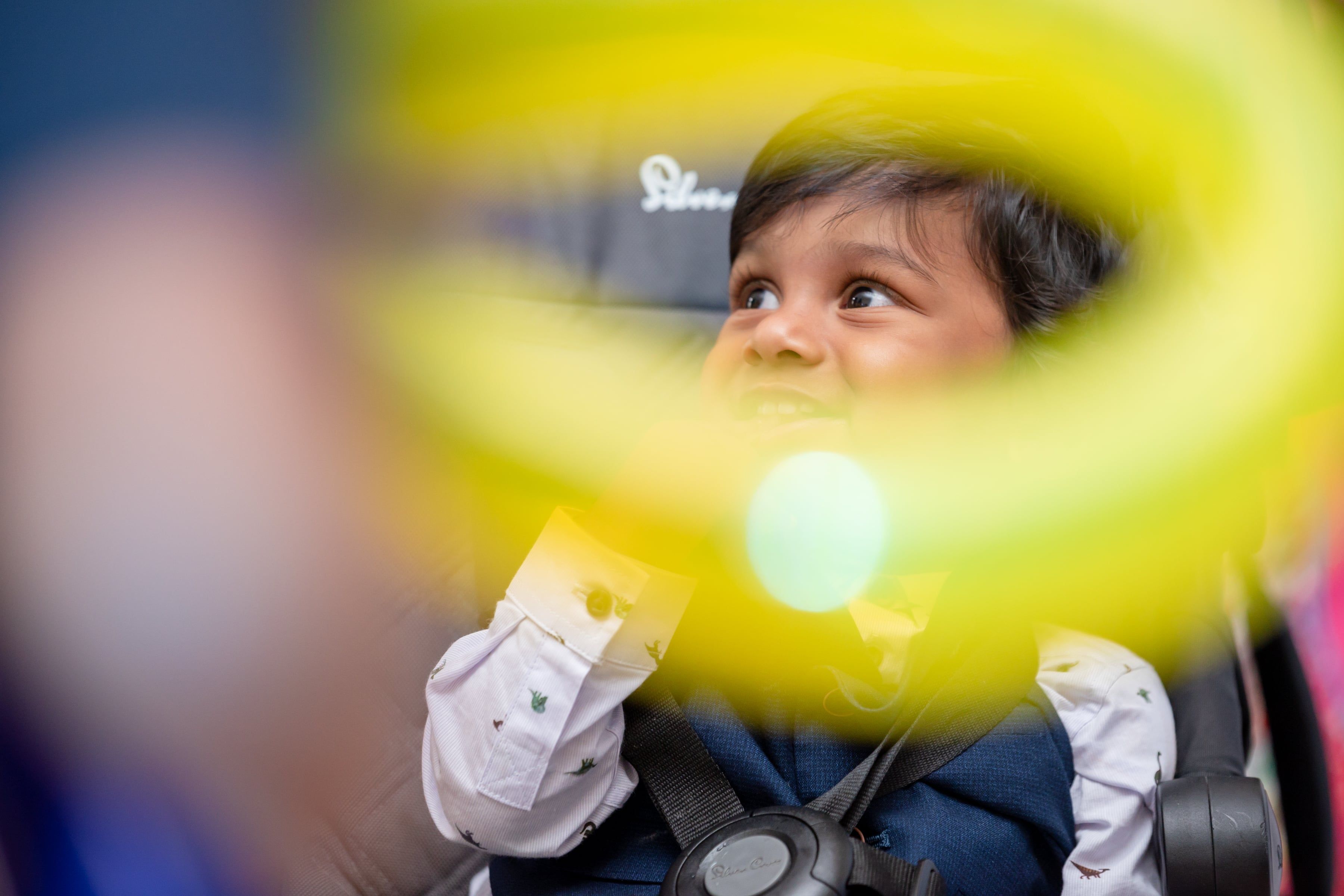 Wide-eyed little boy peeks past a bright balloon at his birthday party