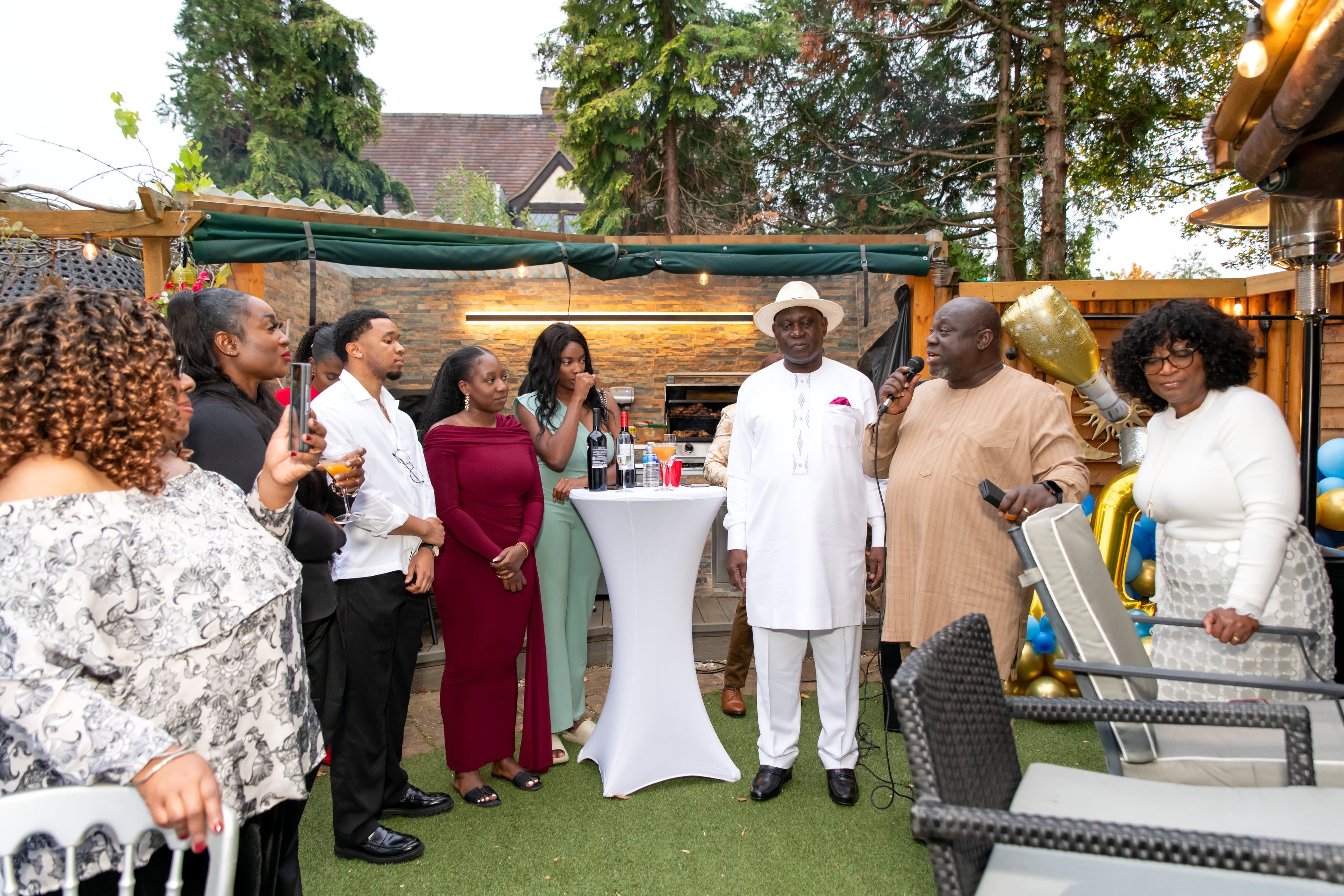 Guests gather for the speeches beside the gold 70 balloons at a seventieth-birthday garden party