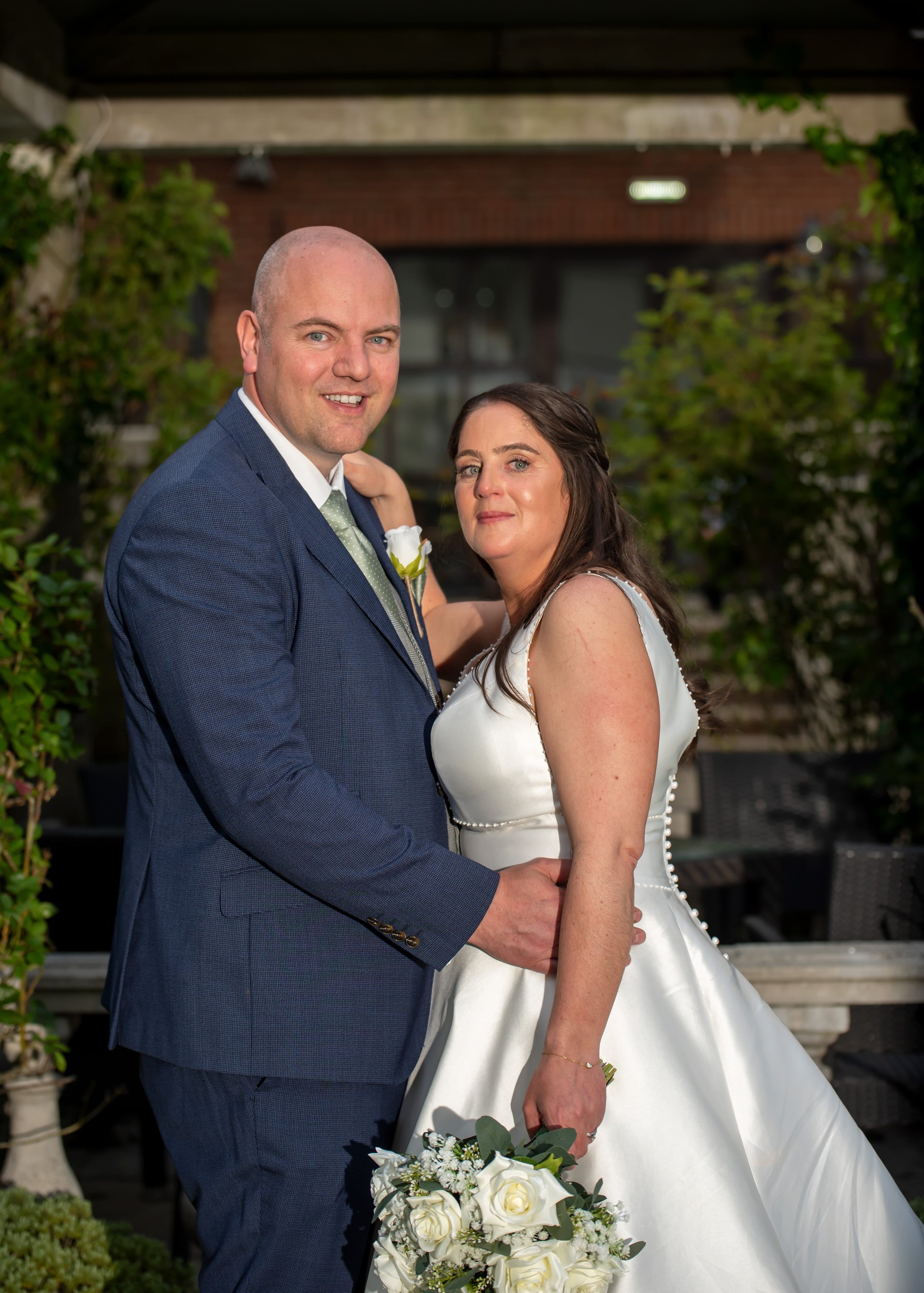 Bride and groom embrace among greenery at Oxford Belfry evening portrait