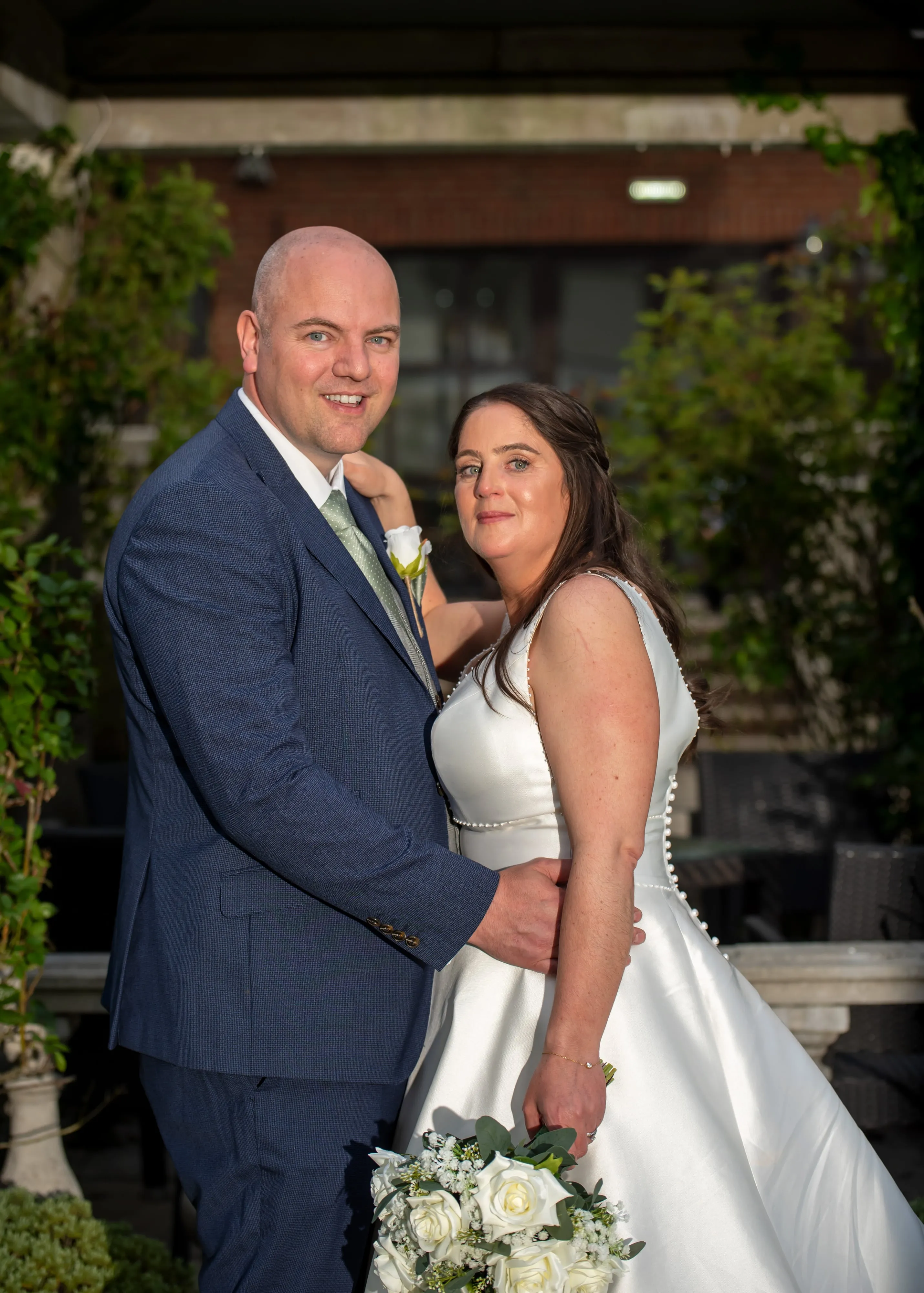 Bride and groom embrace among greenery at Oxford Belfry evening portrait