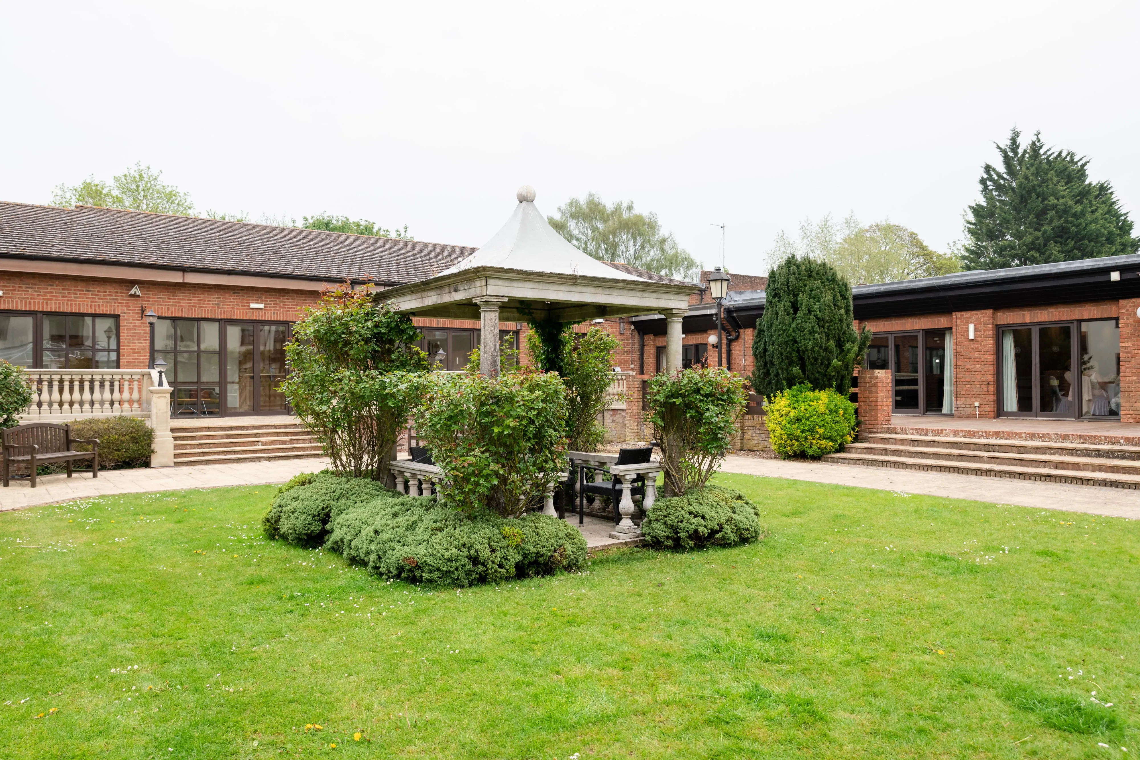 Wide view of the Belfry courtyard with the stone pavilion gazebo and surrounding red-brick wings