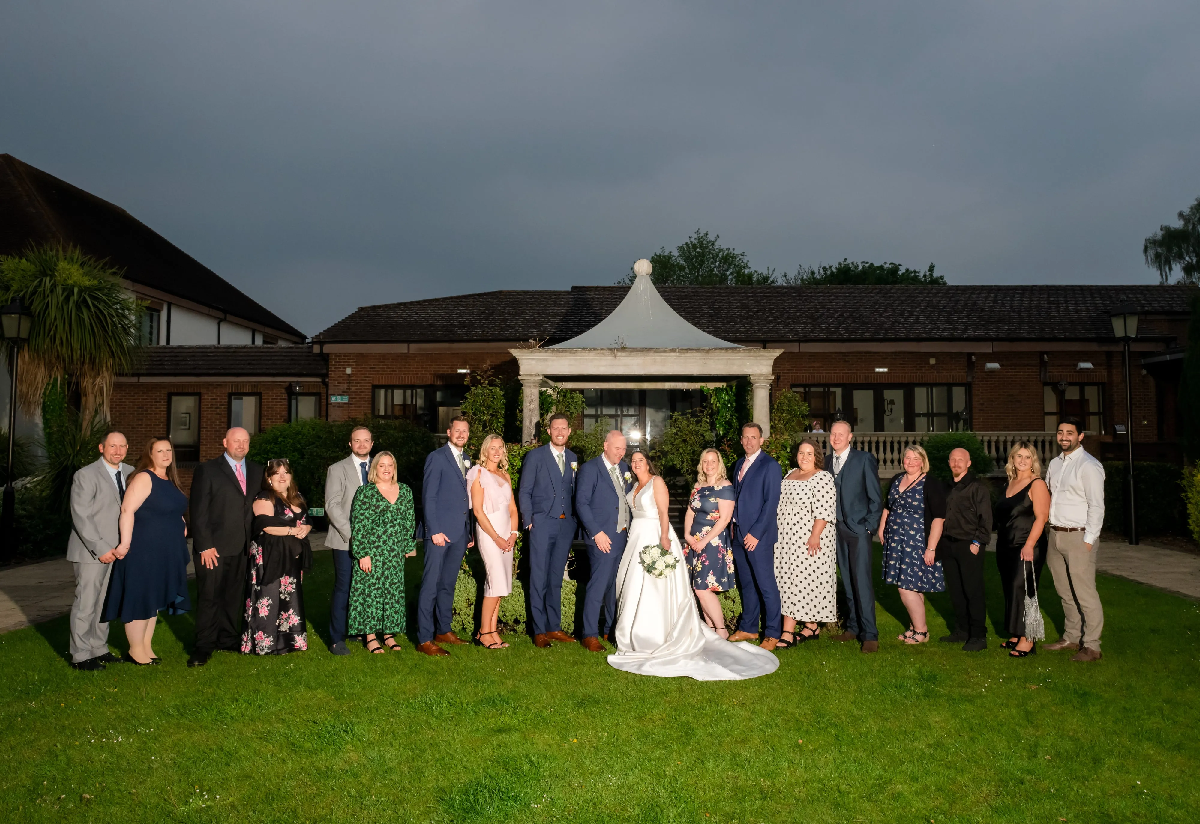 Wedding party gathers in front of Belfry pavilion at twilight group portrait