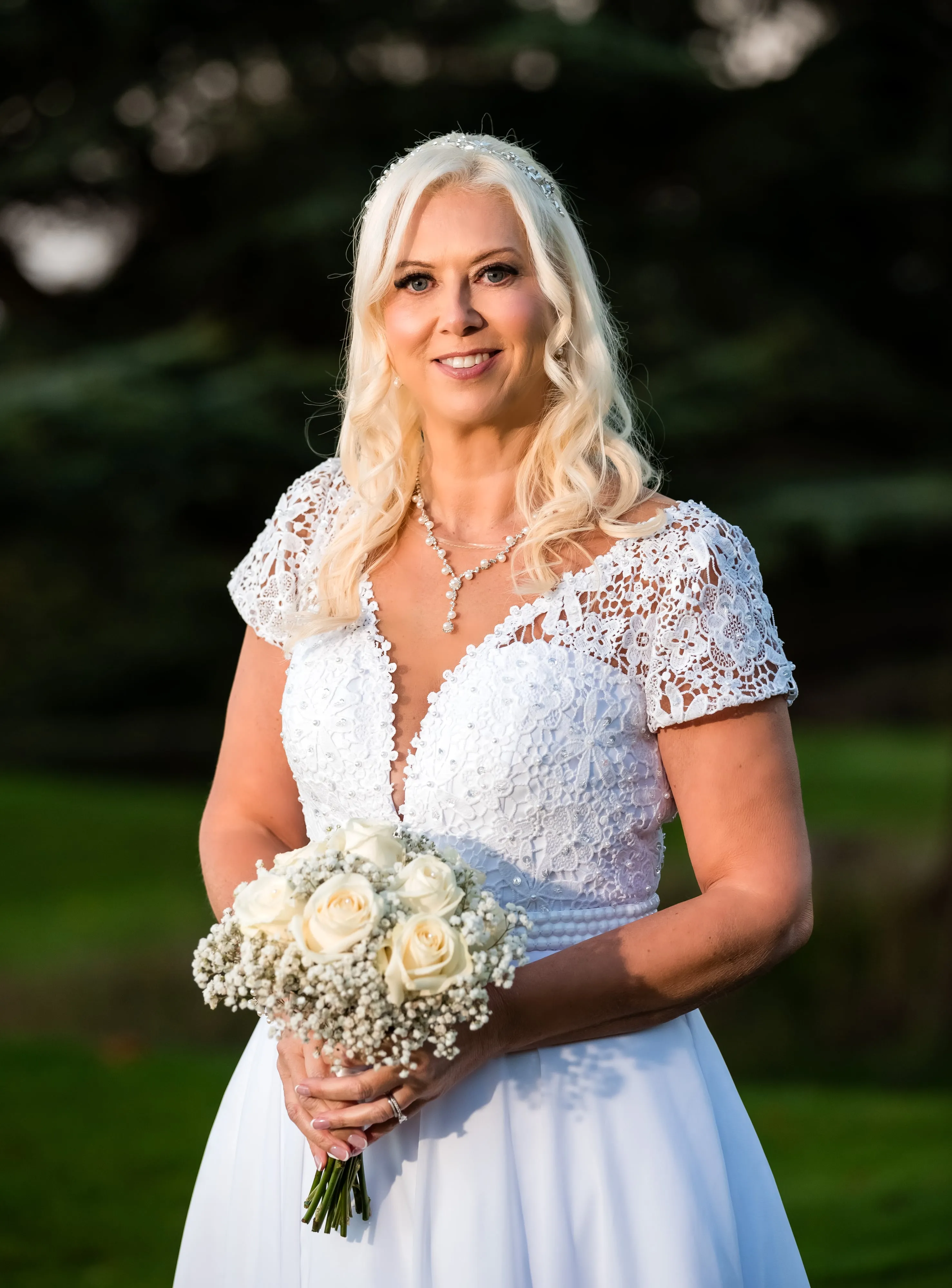 Solo bridal portrait at golden hour at Dyrham Park, white lace gown with rhinestone bodice, holding white-rose bouquet