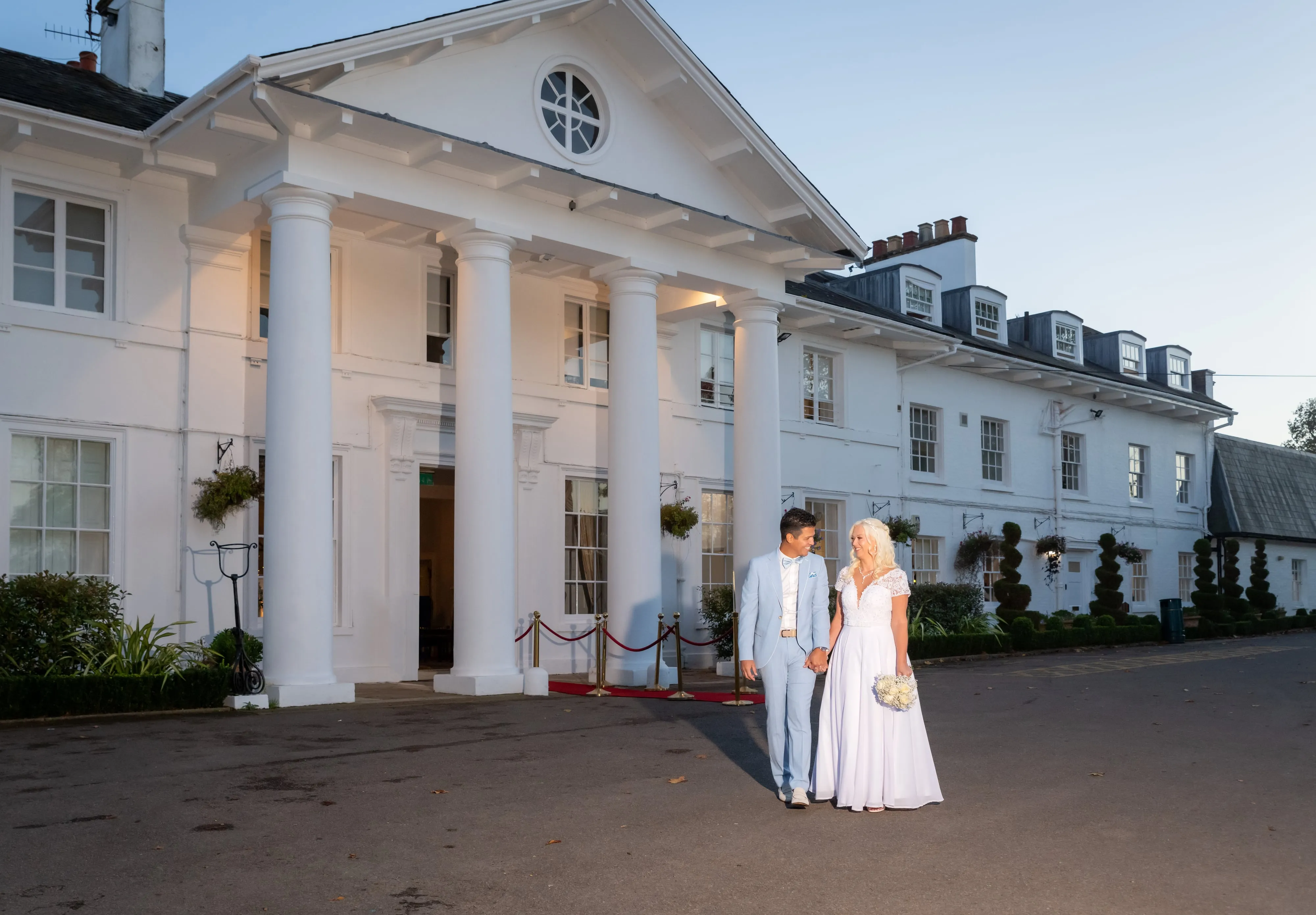 Bride and groom hands at dusk holding rings at Dyrham Park