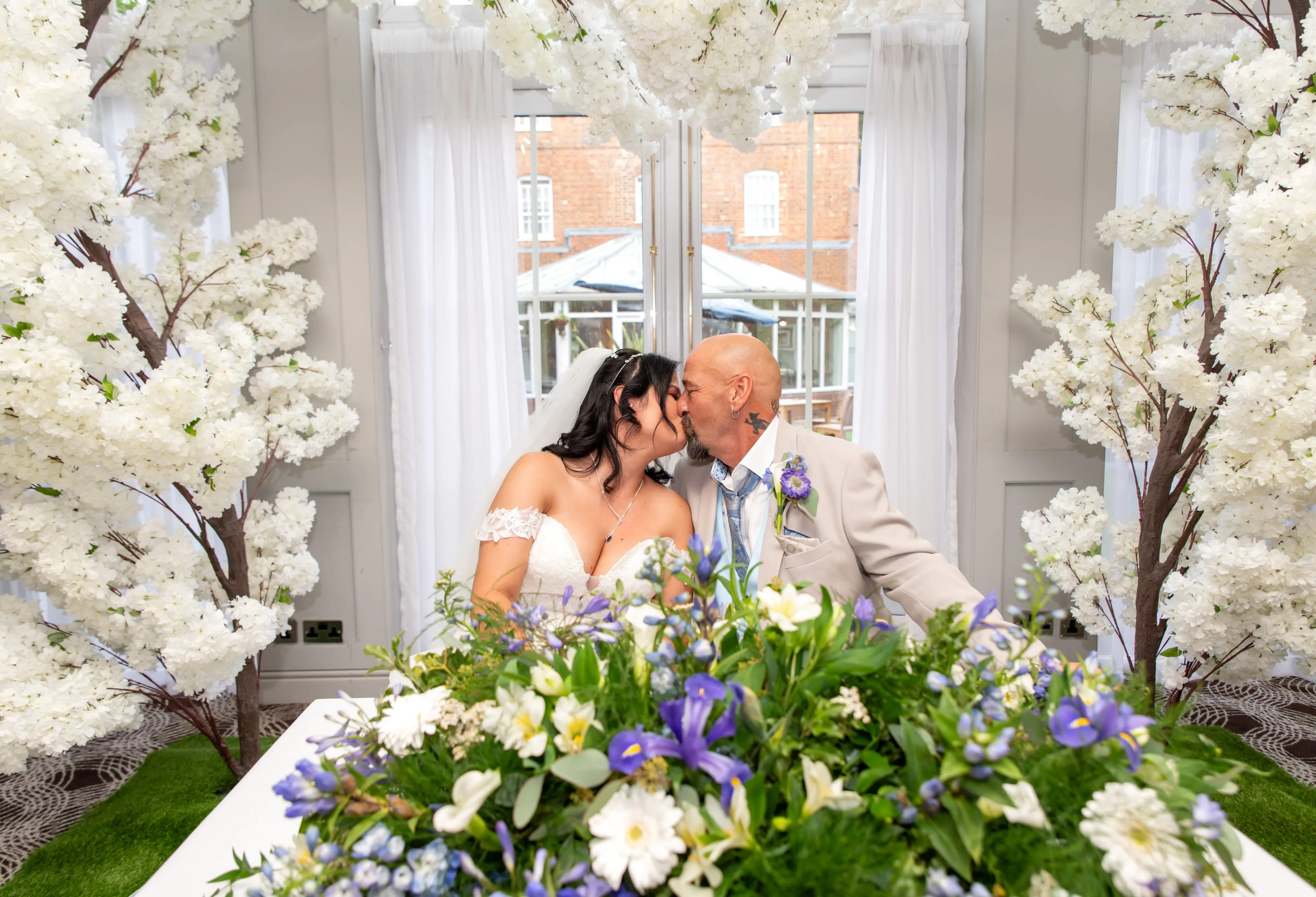 Bride and groom kiss at blossom-decorated ceremony arch