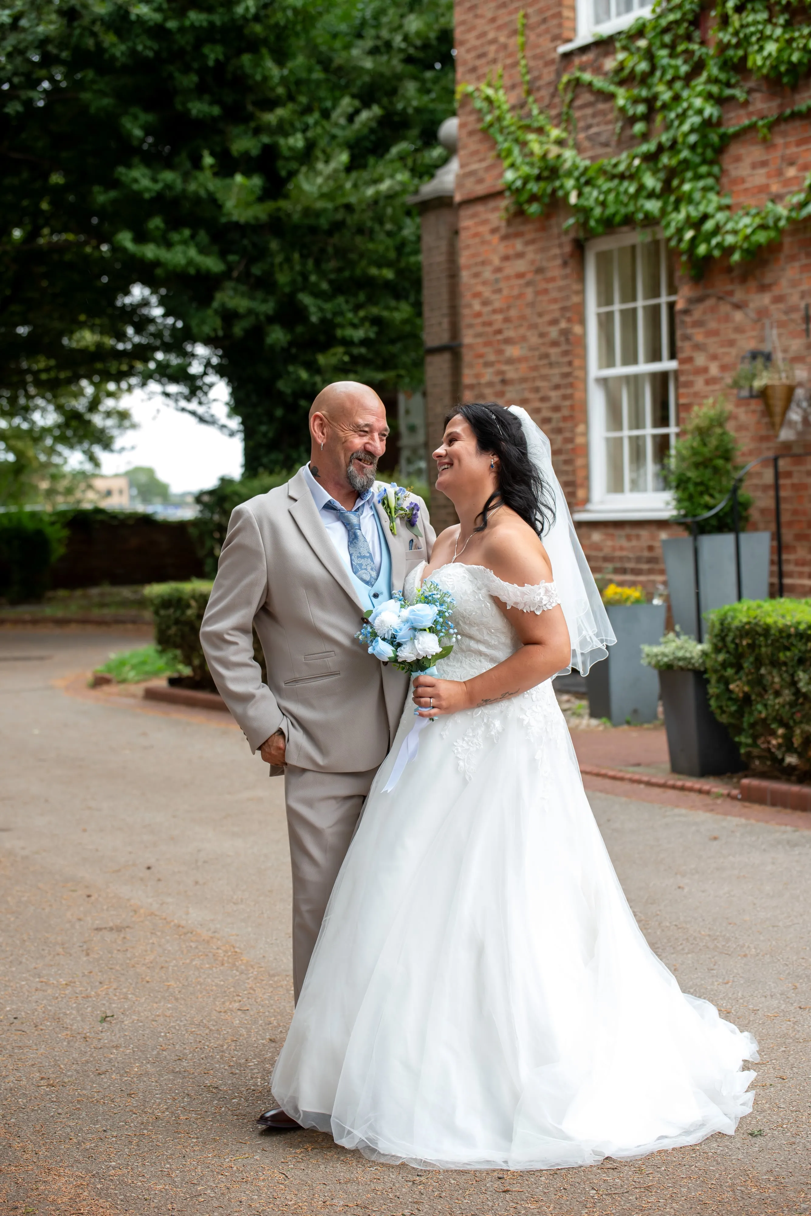 Bride laughs with her father as they share a moment outside the ivy-clad Holiday Inn entrance