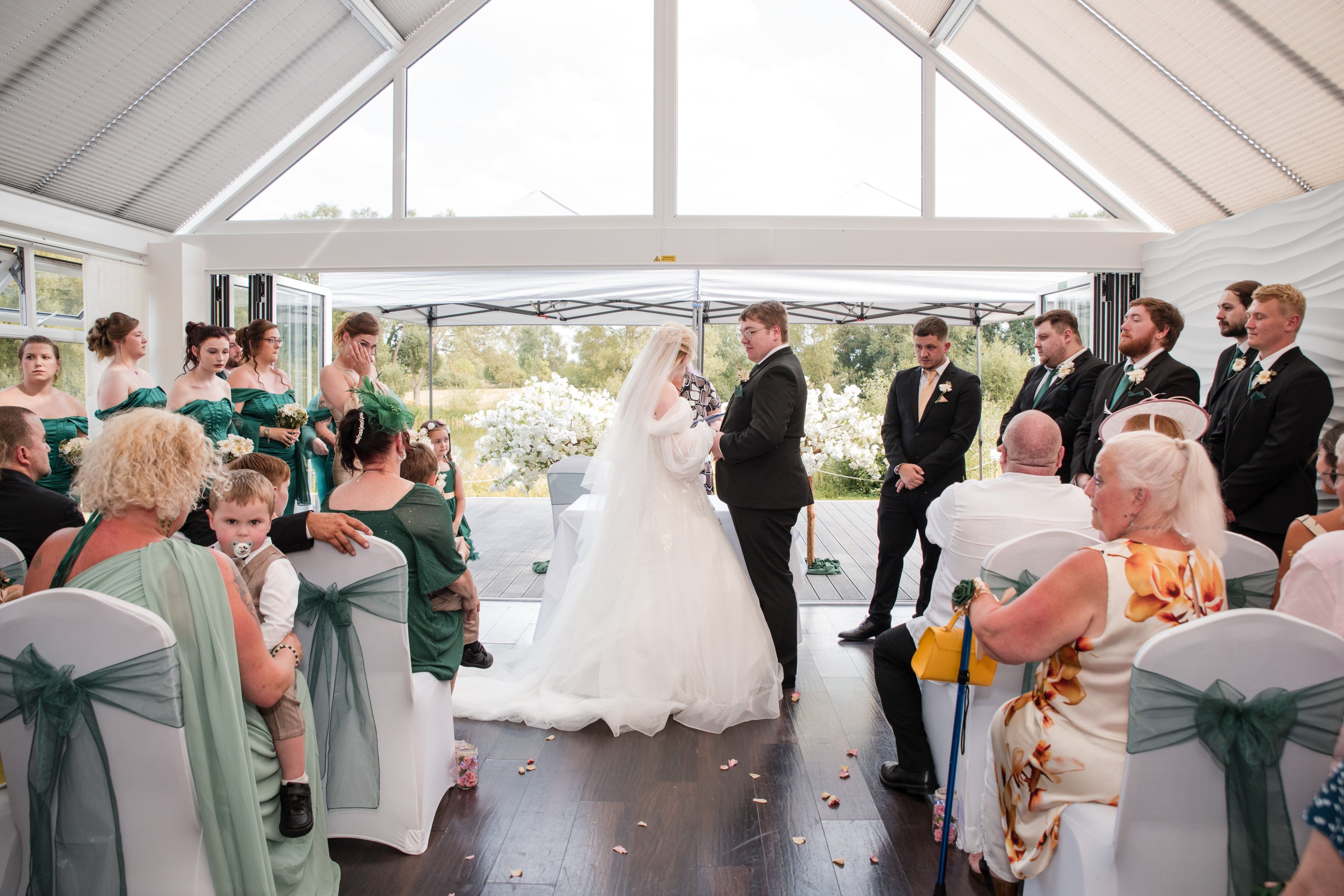 Bride and groom exchange vows before the celebrant as guests look on