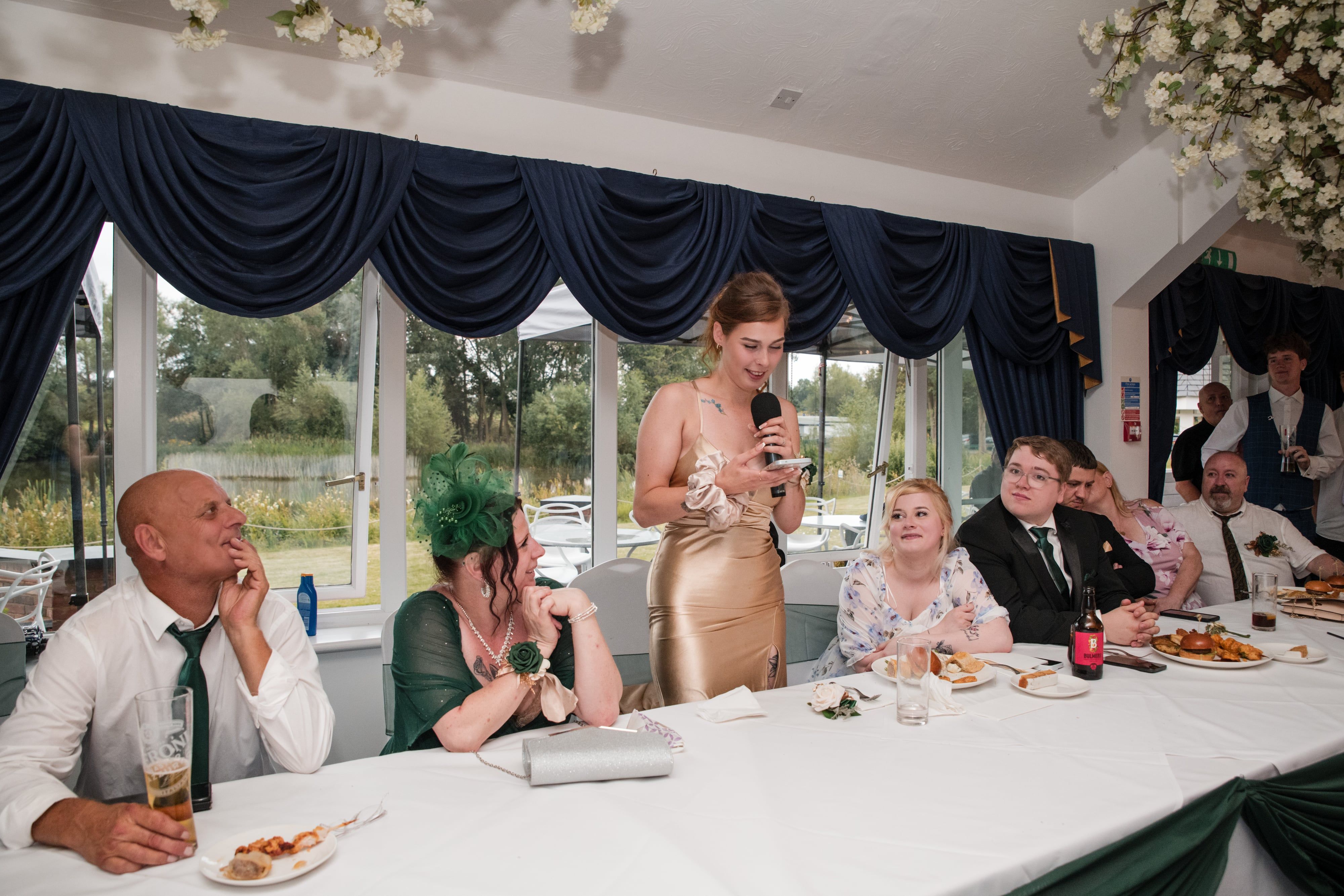 Maid of honour reads her speech at the wedding breakfast, top table listening