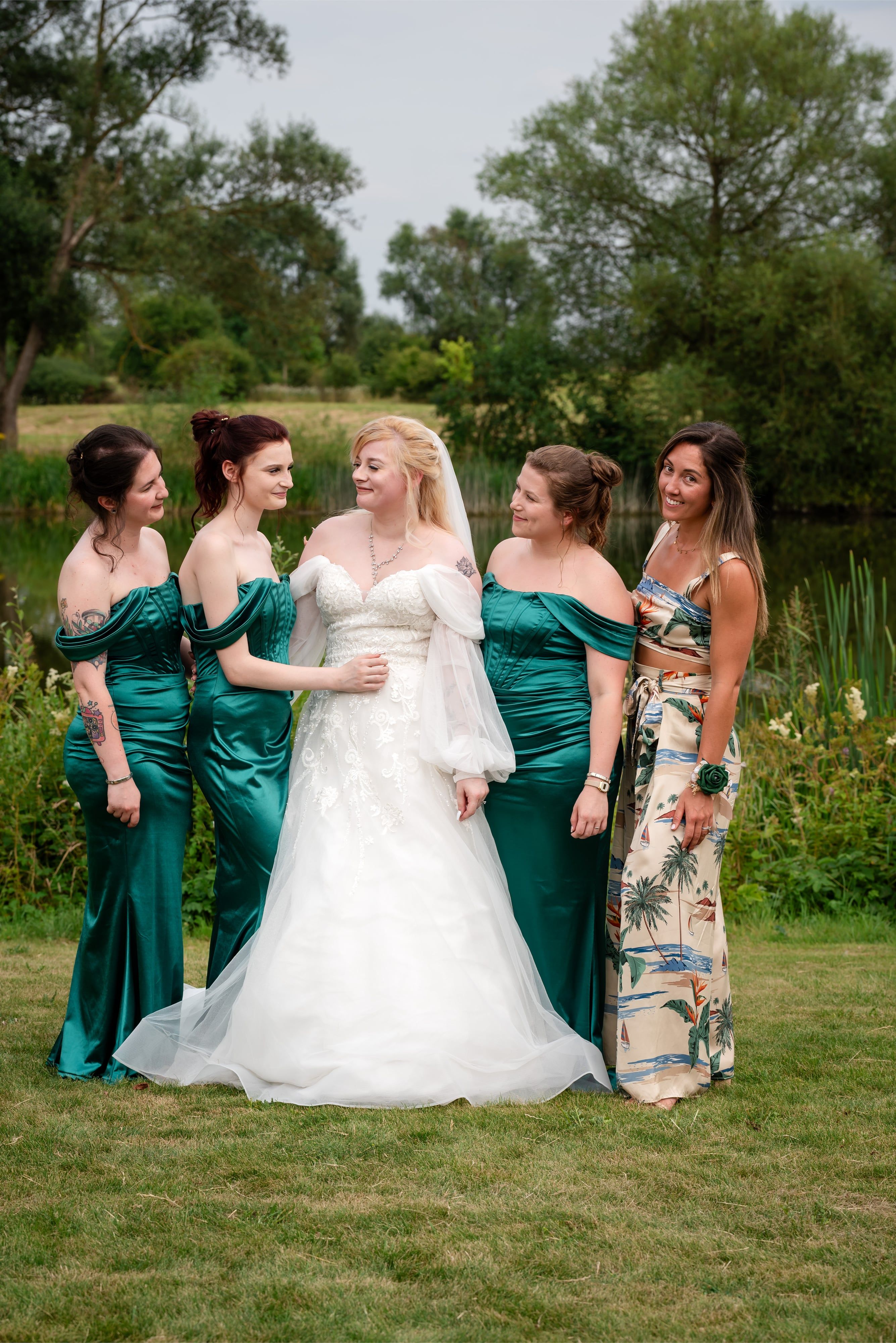 Bride with four bridesmaids in emerald green on the lakeside lawn