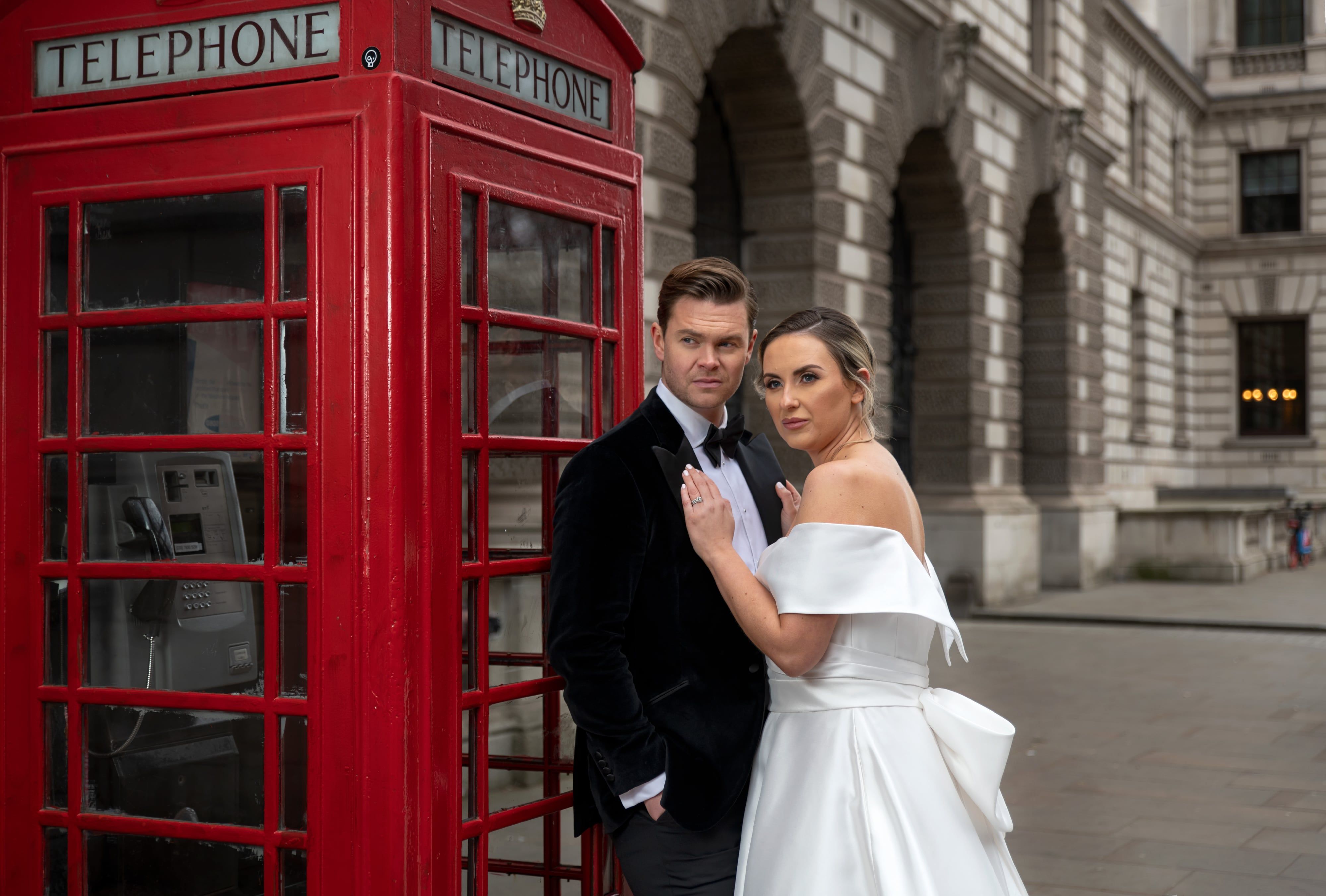 Bride and groom by red telephone box on a London wedding day