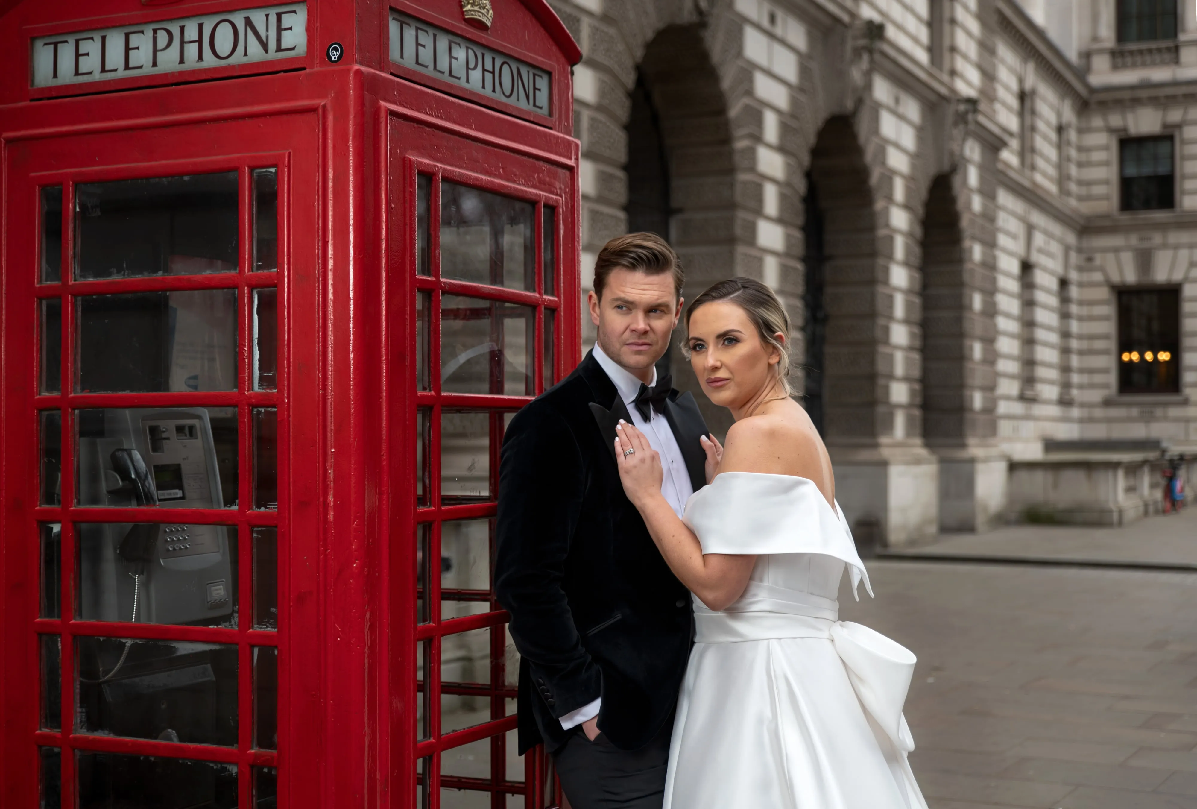 Bride and groom by red telephone box on a London wedding day