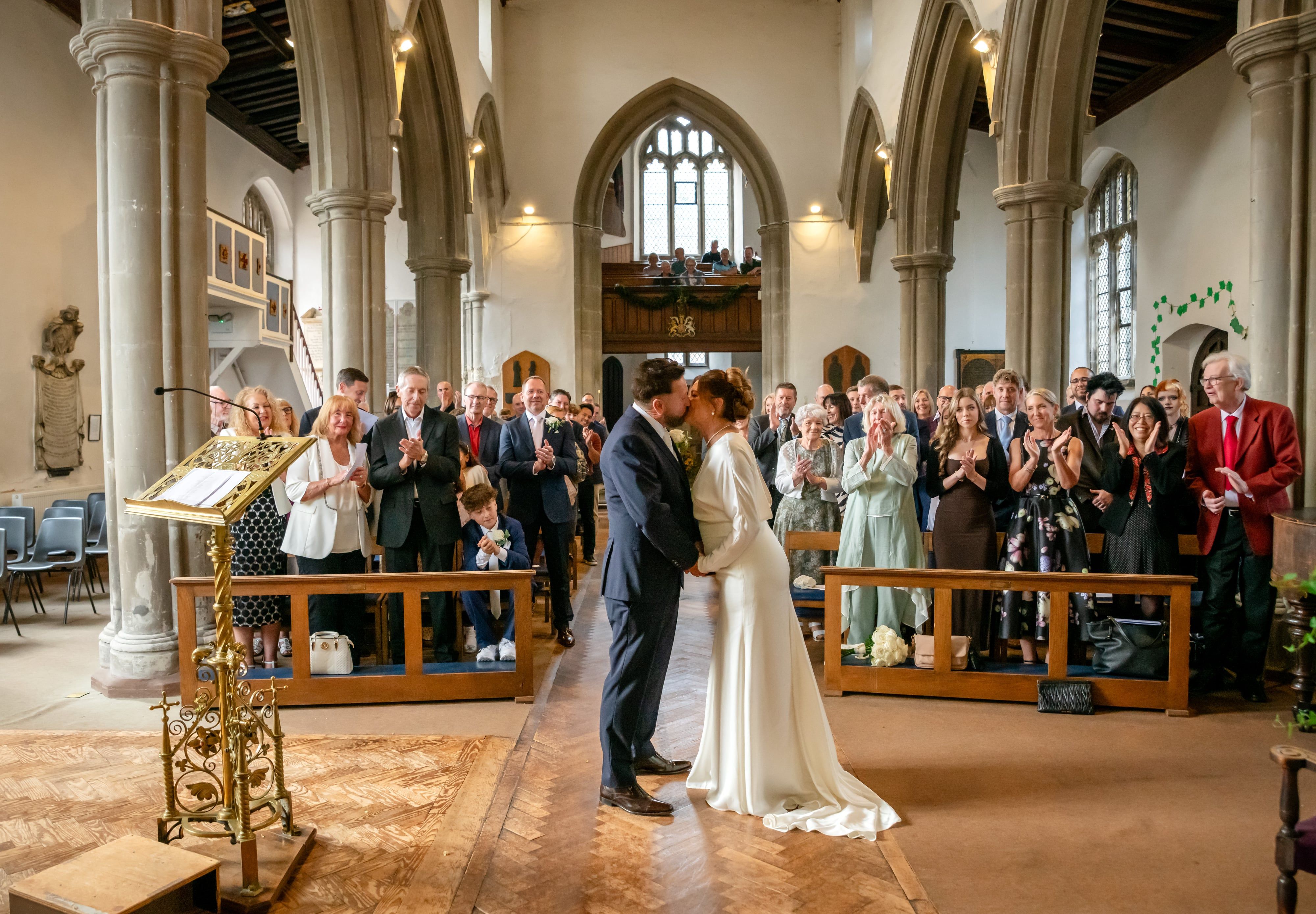 First kiss in the nave of St Andrew's Church, Ampthill, as guests applaud from the pews and gallery
