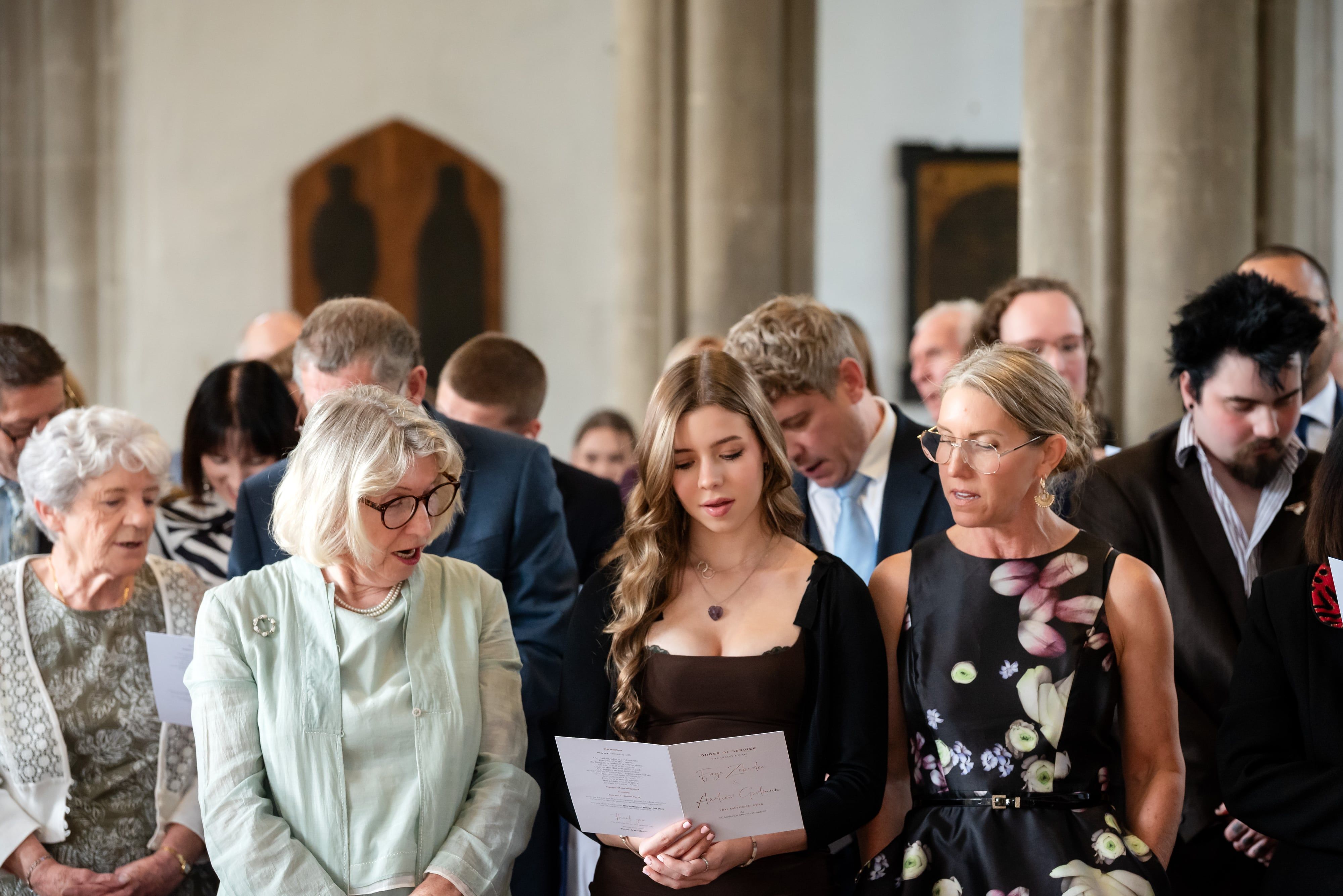 Wedding guests follow the order of service between stone pillars inside St Andrew's Church, Ampthill