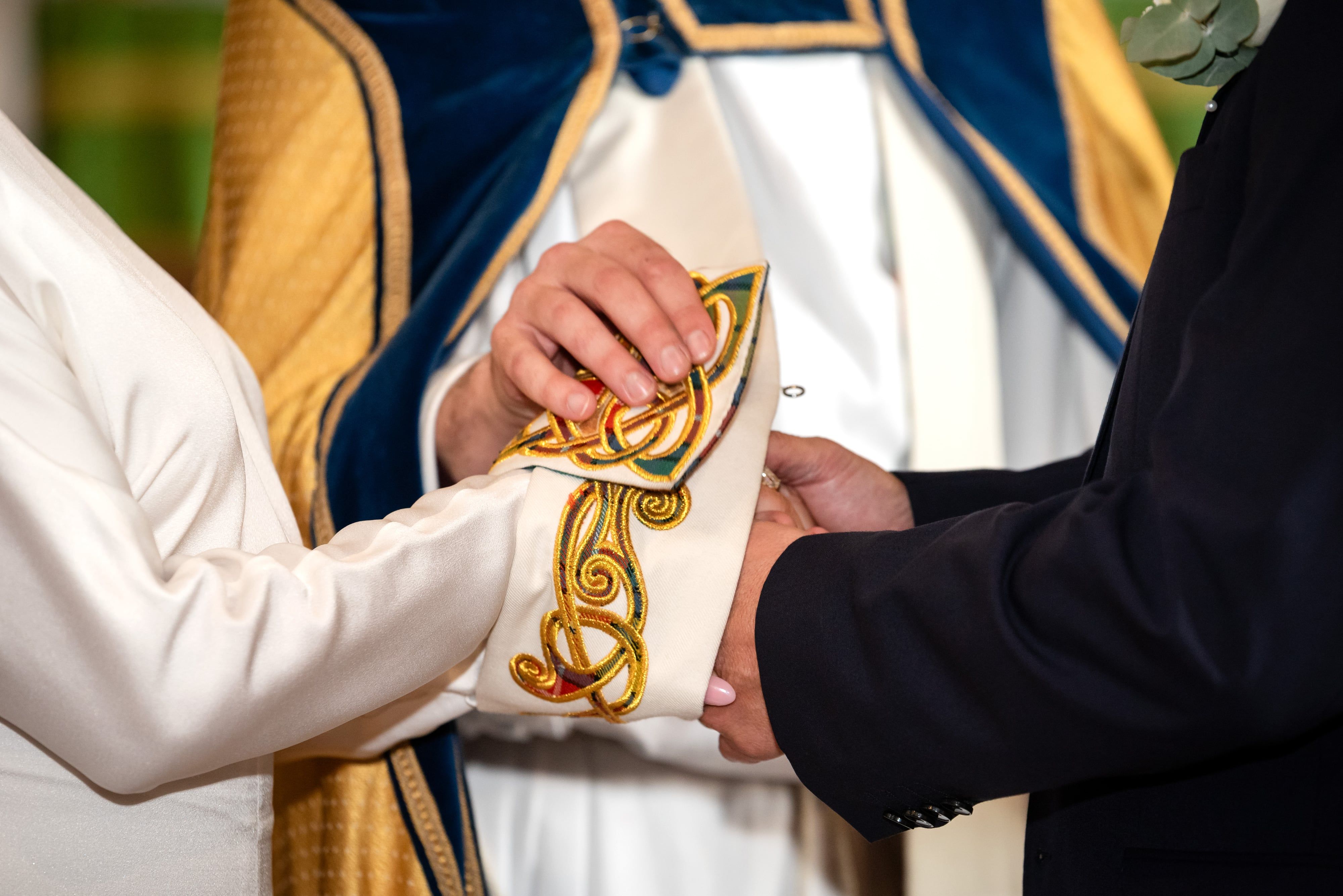 Gold-embroidered stole wrapped around the couple's joined hands during the wedding blessing
