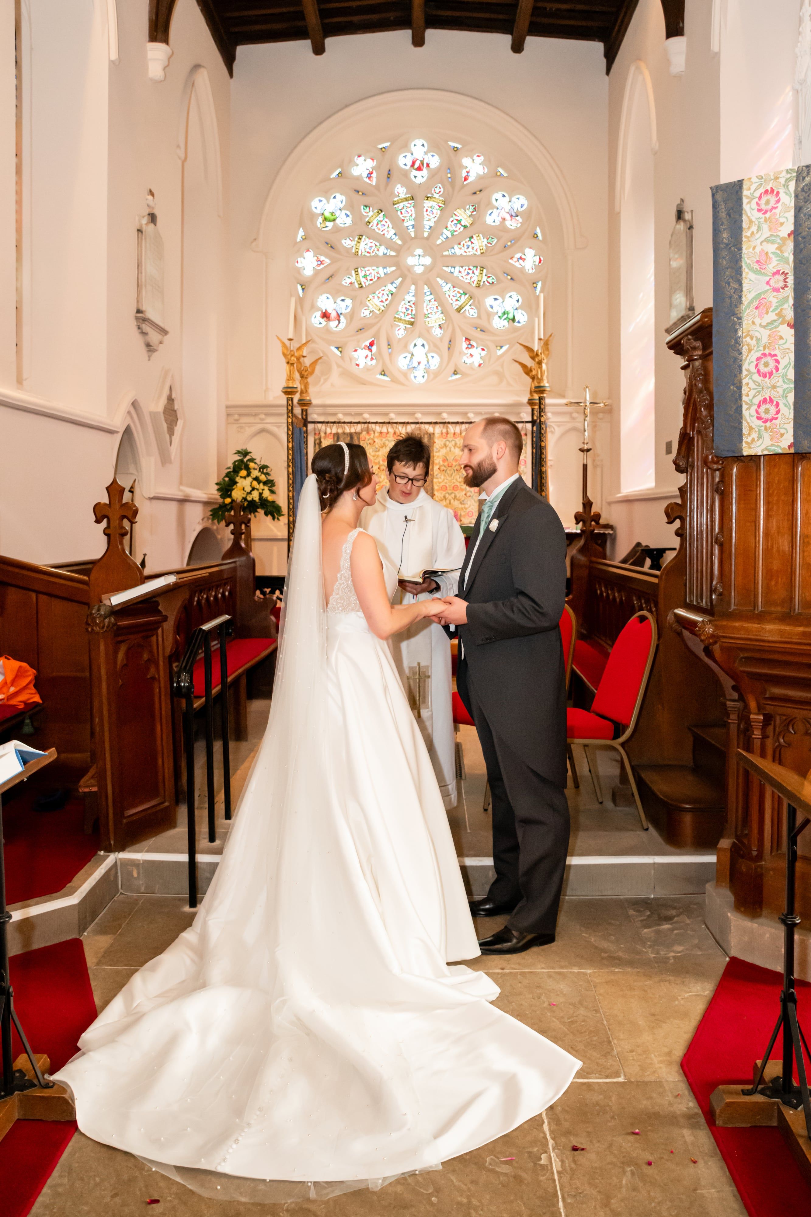 Couple exchange vows beneath the circular rose window at the chancel steps