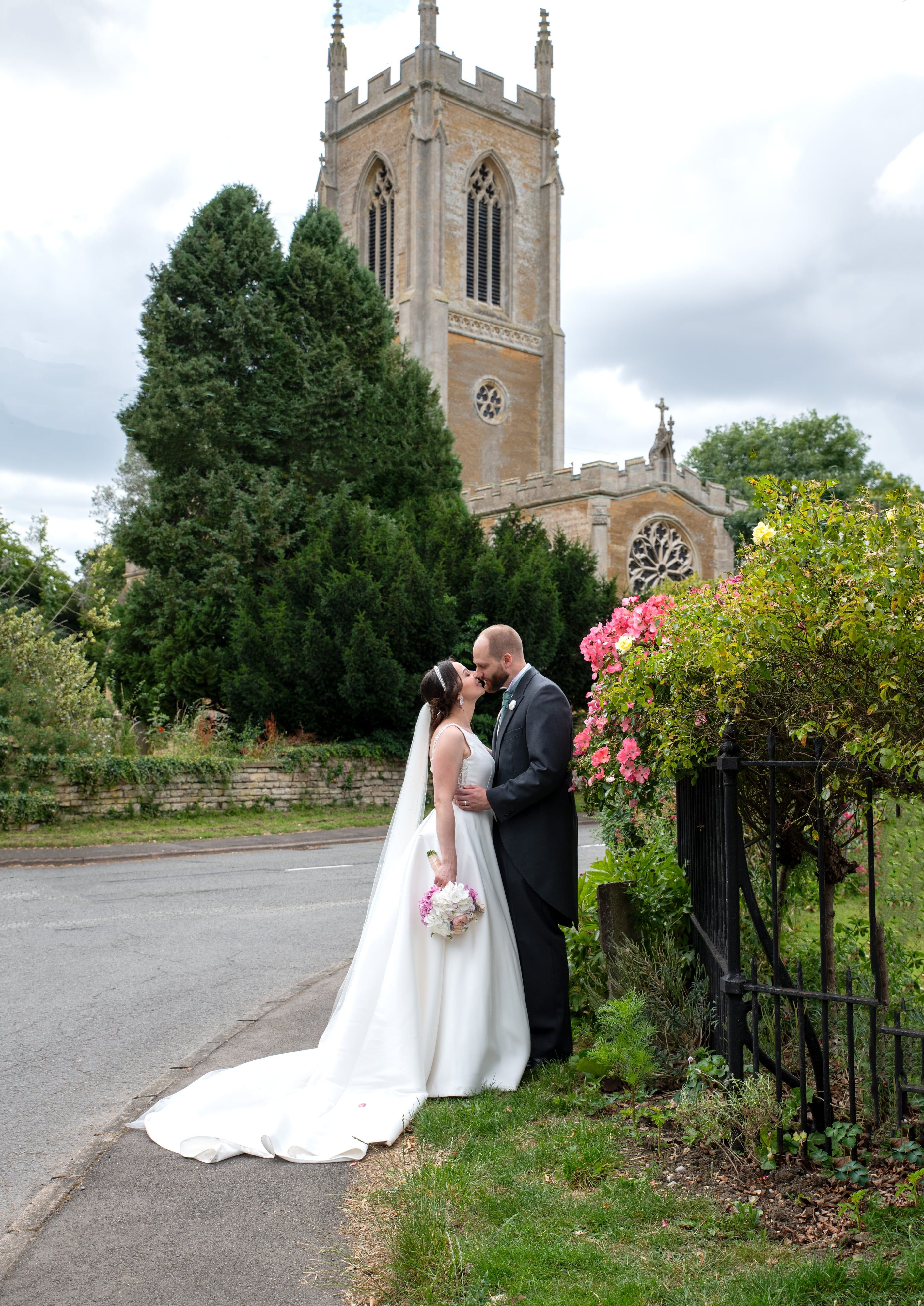 Couple kiss at the churchyard gate below St Mary's embattled central tower