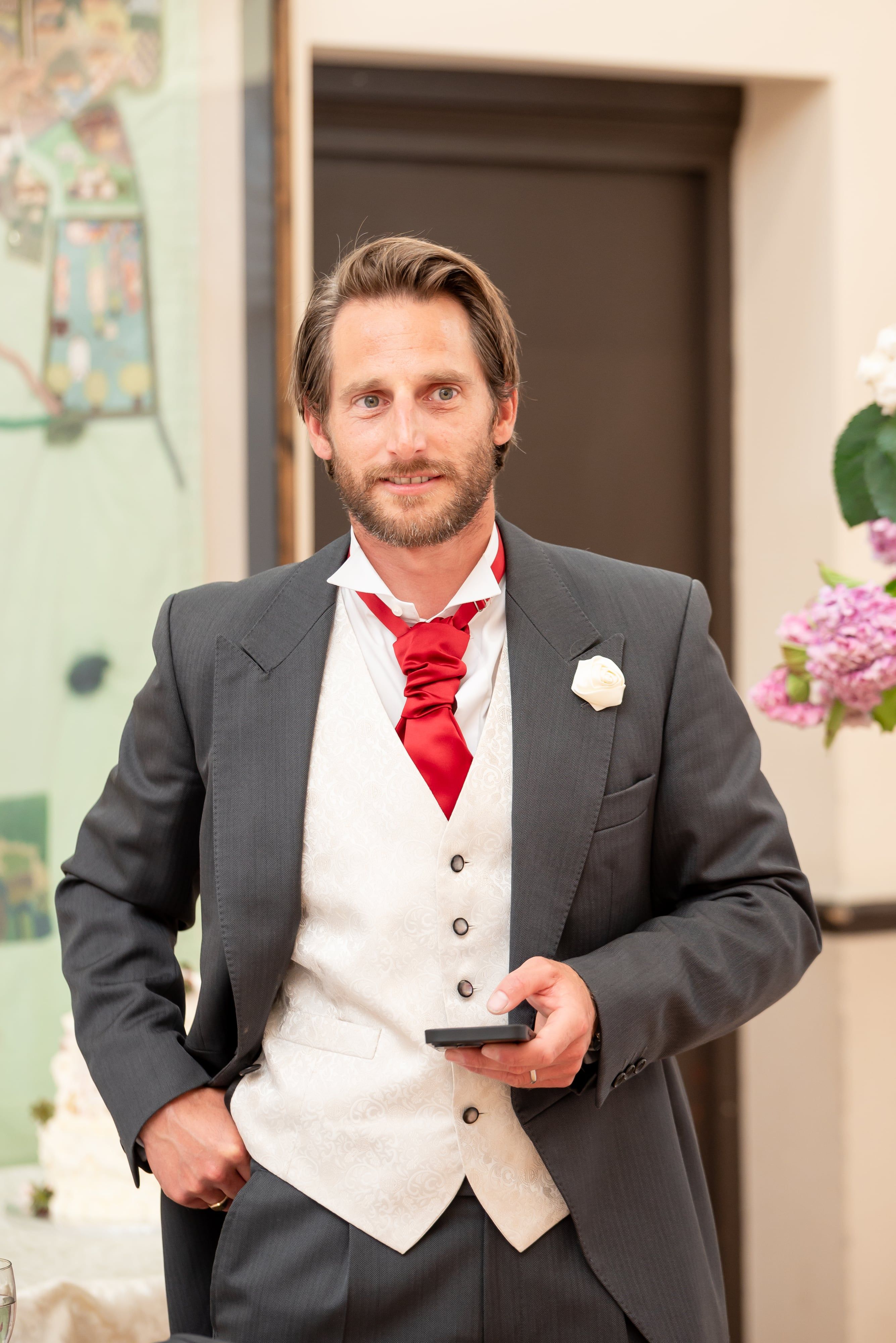 Member of the wedding party in red cravat and patterned waistcoat at the reception