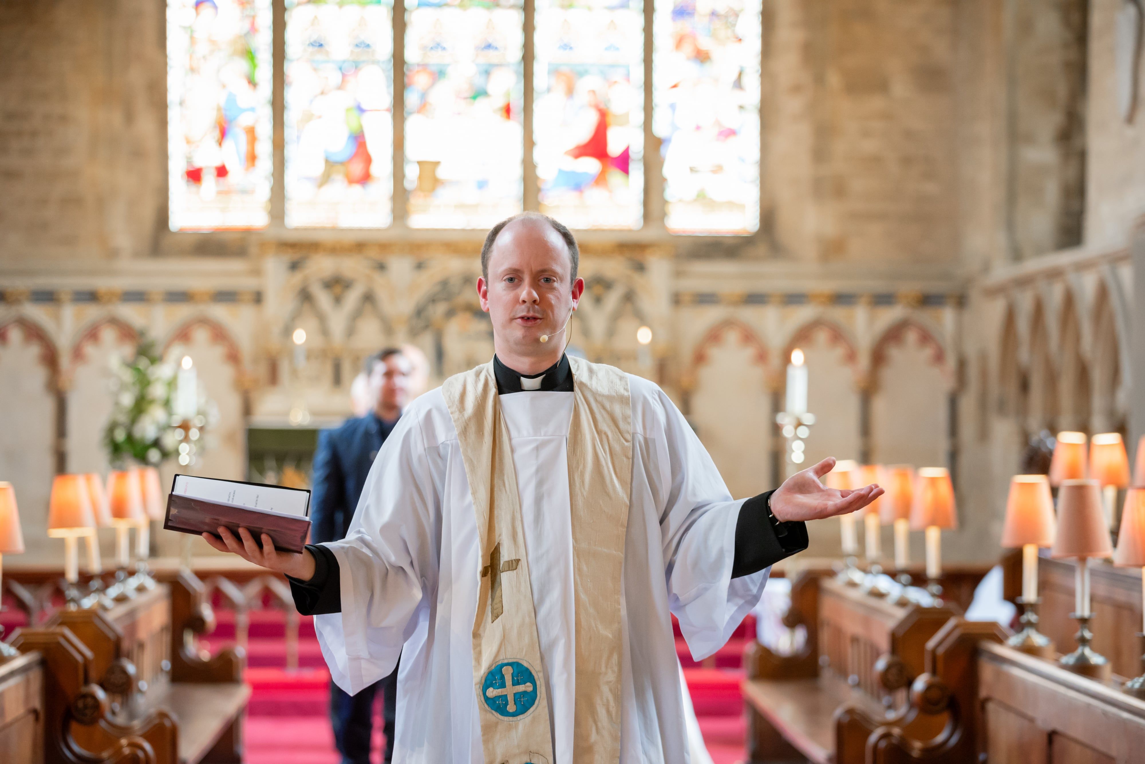 The vicar addresses the congregation from the chancel steps, candles lit either side