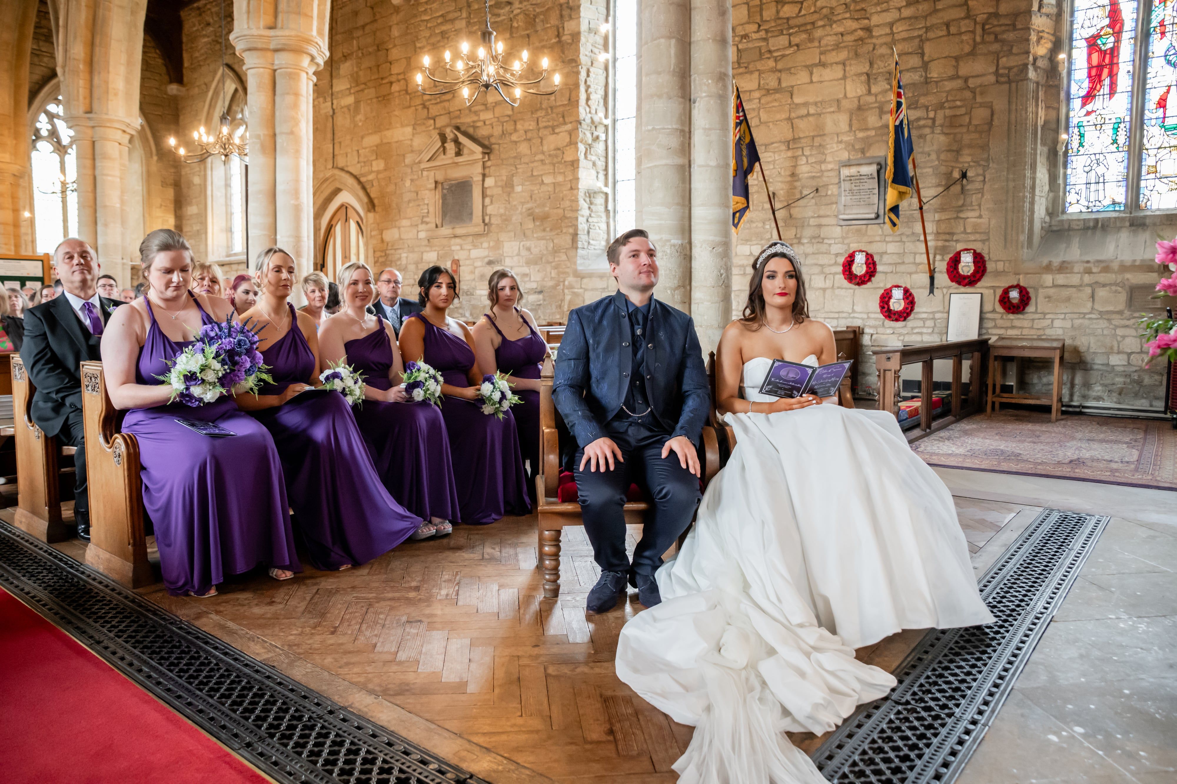 Bride and groom seated at the chancel with bridesmaids and family in the pews behind
