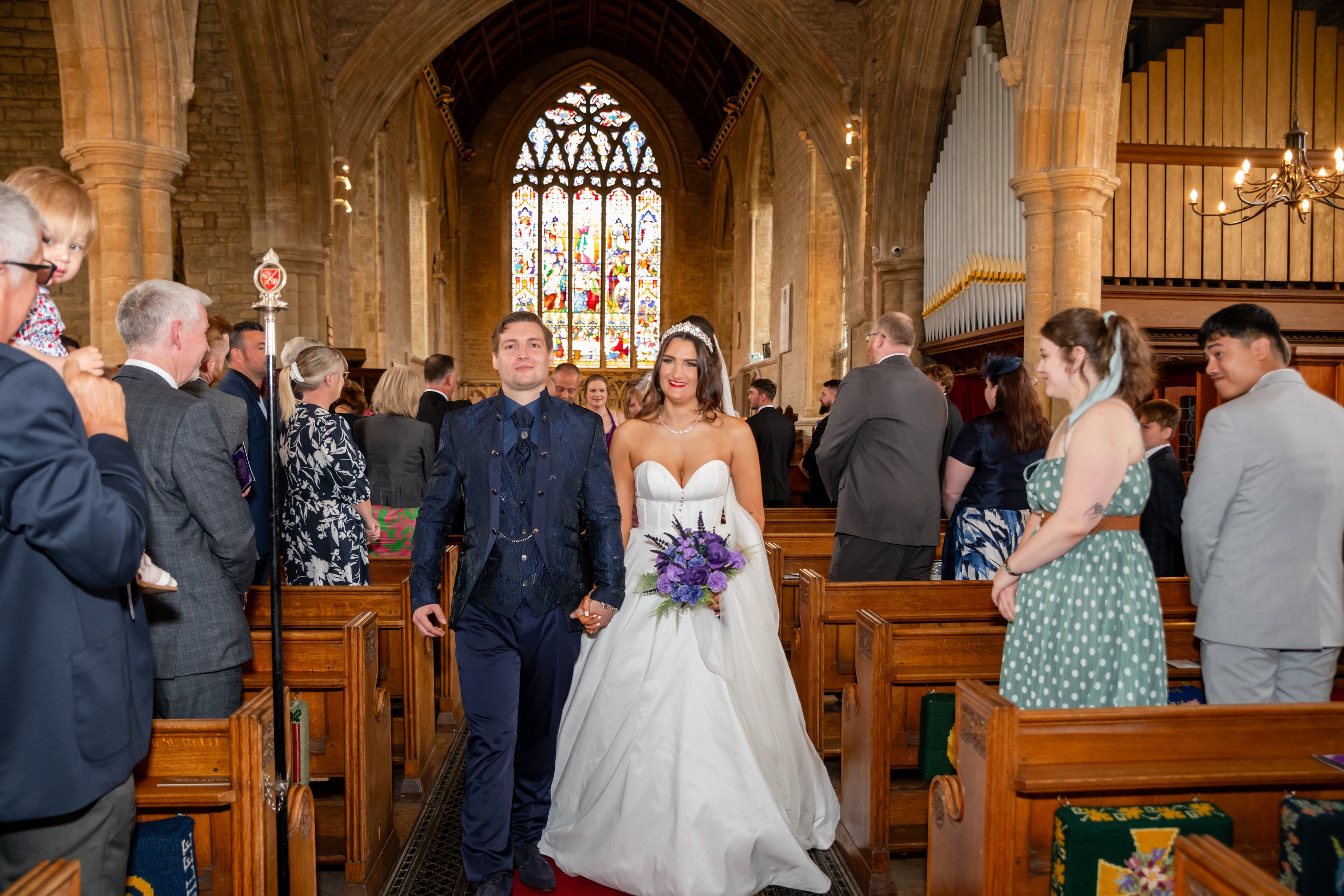 Newlyweds walk back down the aisle beneath the stained-glass west window