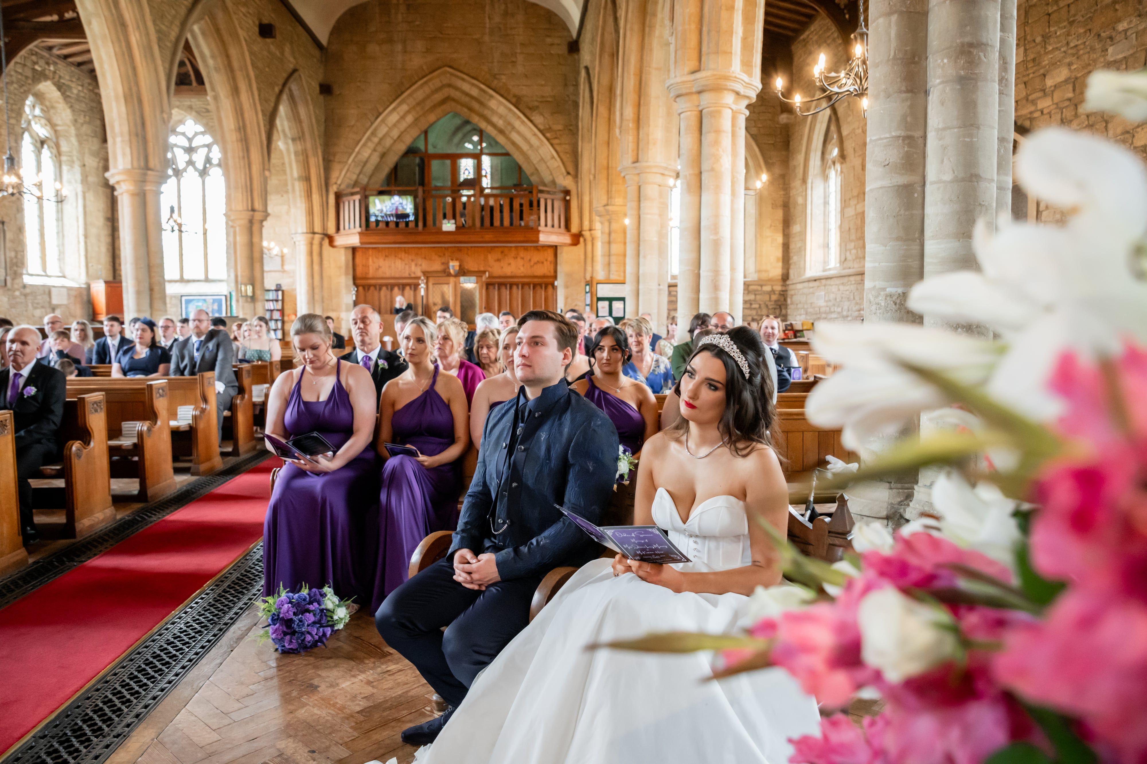 Couple seated during the ceremony with pink lilies in the foreground
