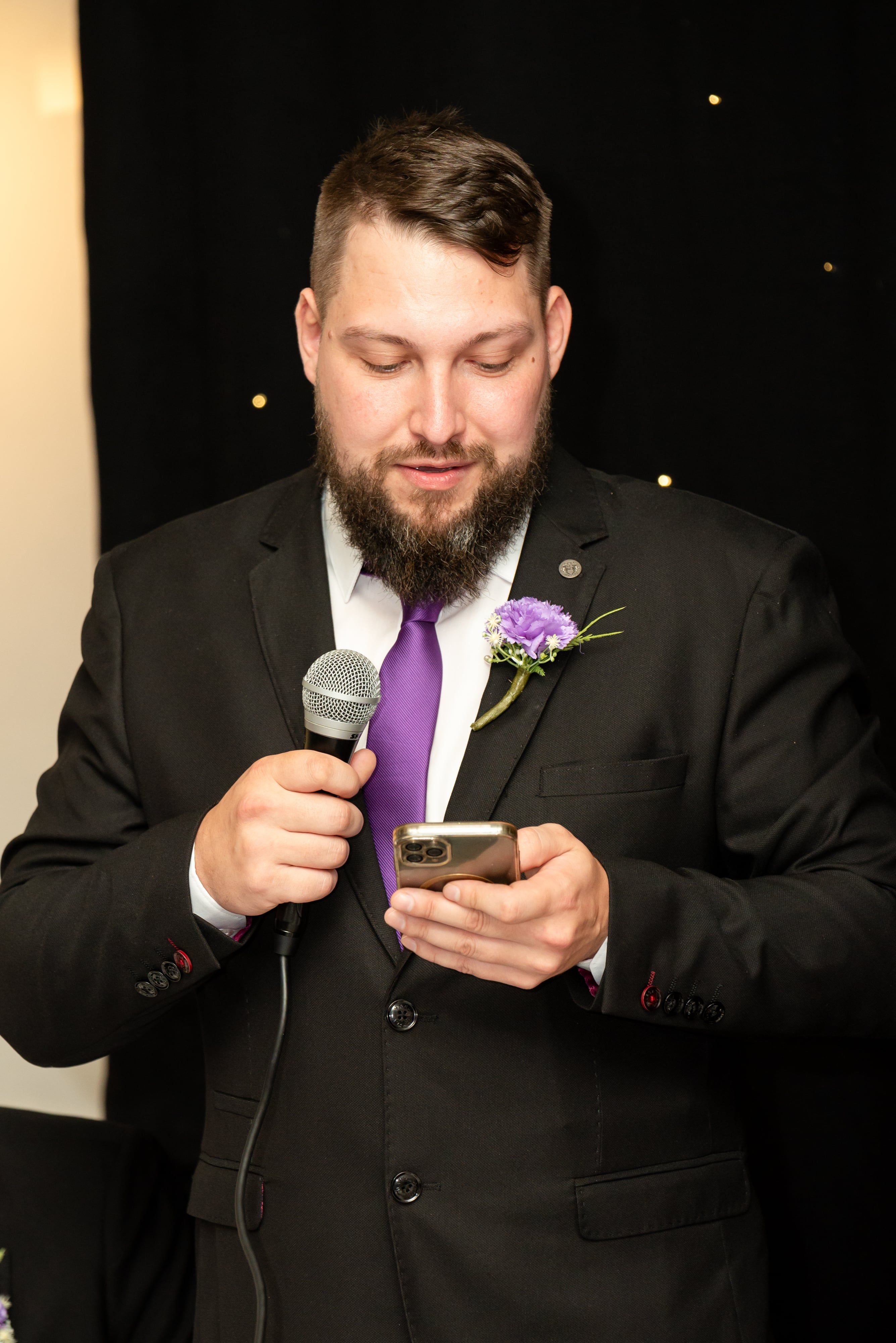 Best man reads his speech from his phone against the starlight backdrop